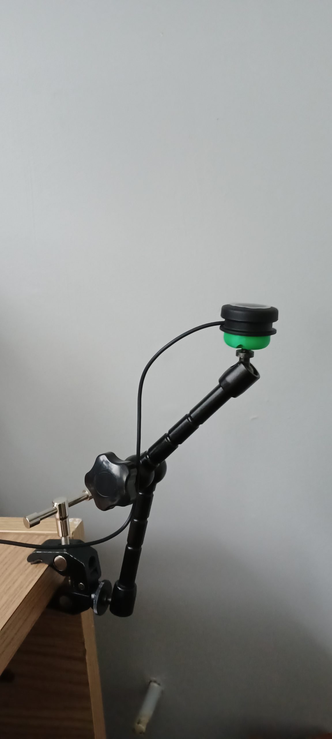 A green 3d printed mounting base attached to a black Logitech large button.