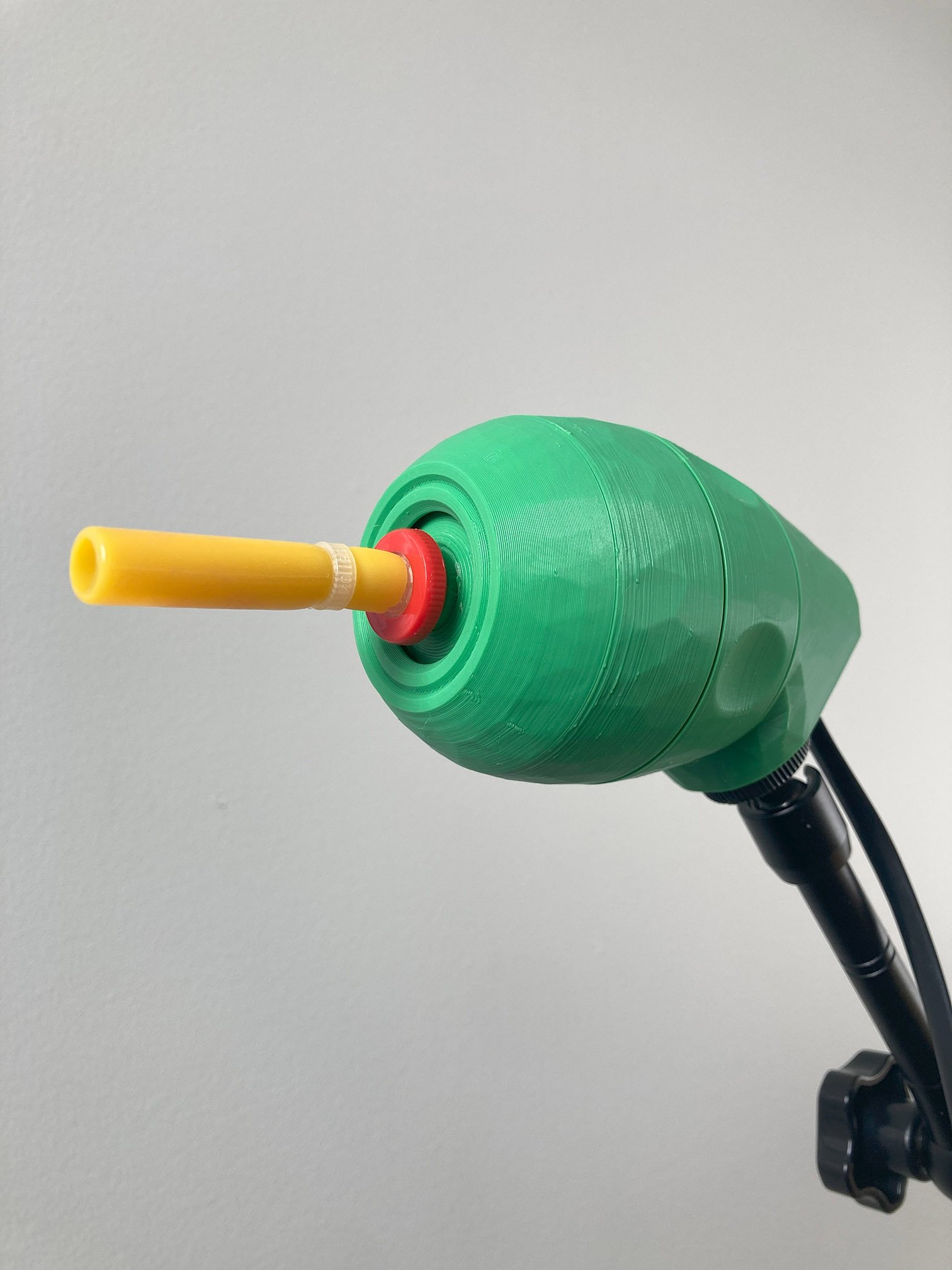 A green 3D printed LipSync joystick on a black mounting arm