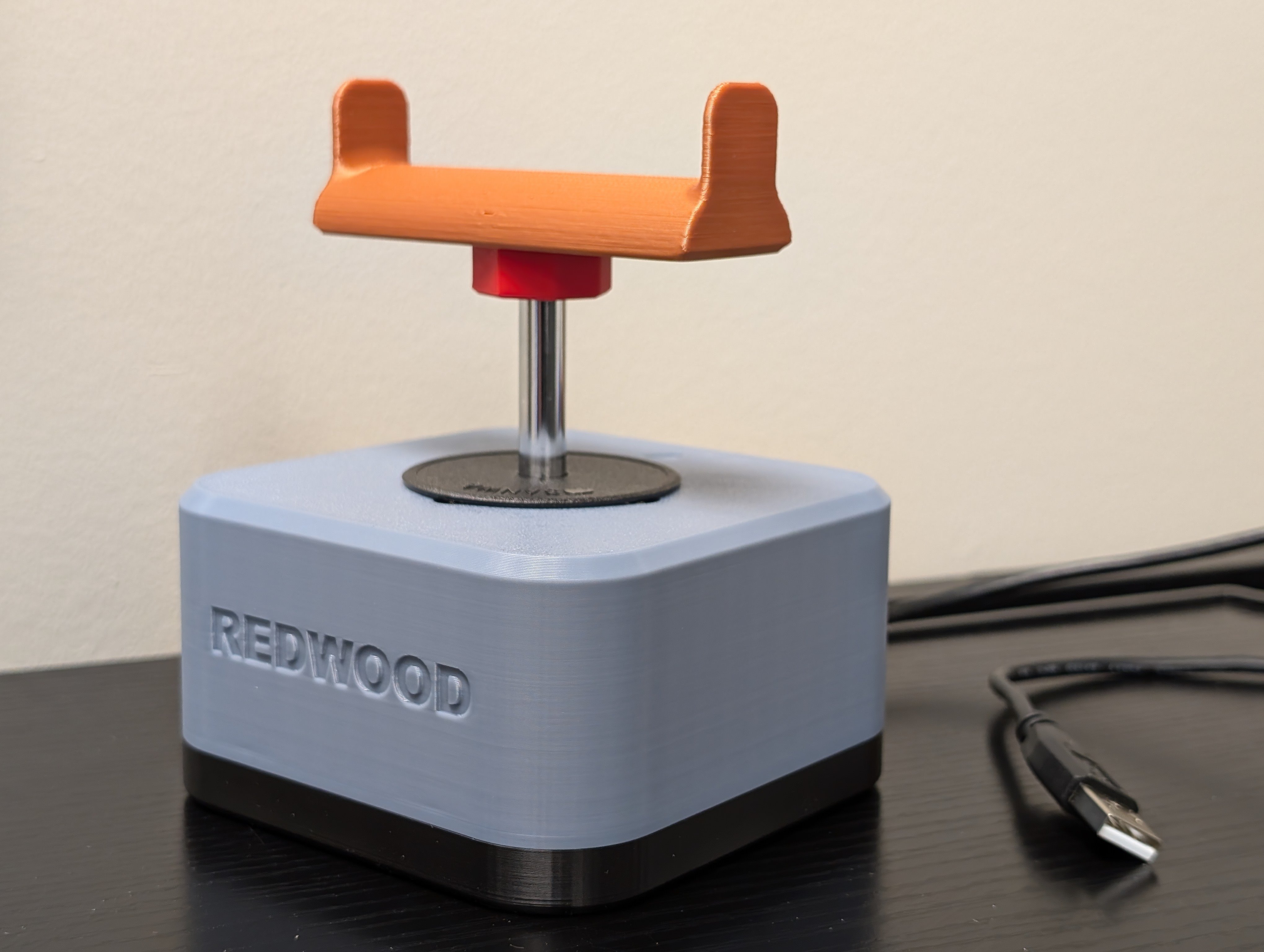 Isometric view of the Redwood joystick with a brown 3D printed goalpost topper. A USB type A cable can be seen on the side. Top enclosure is light blue and base is black.