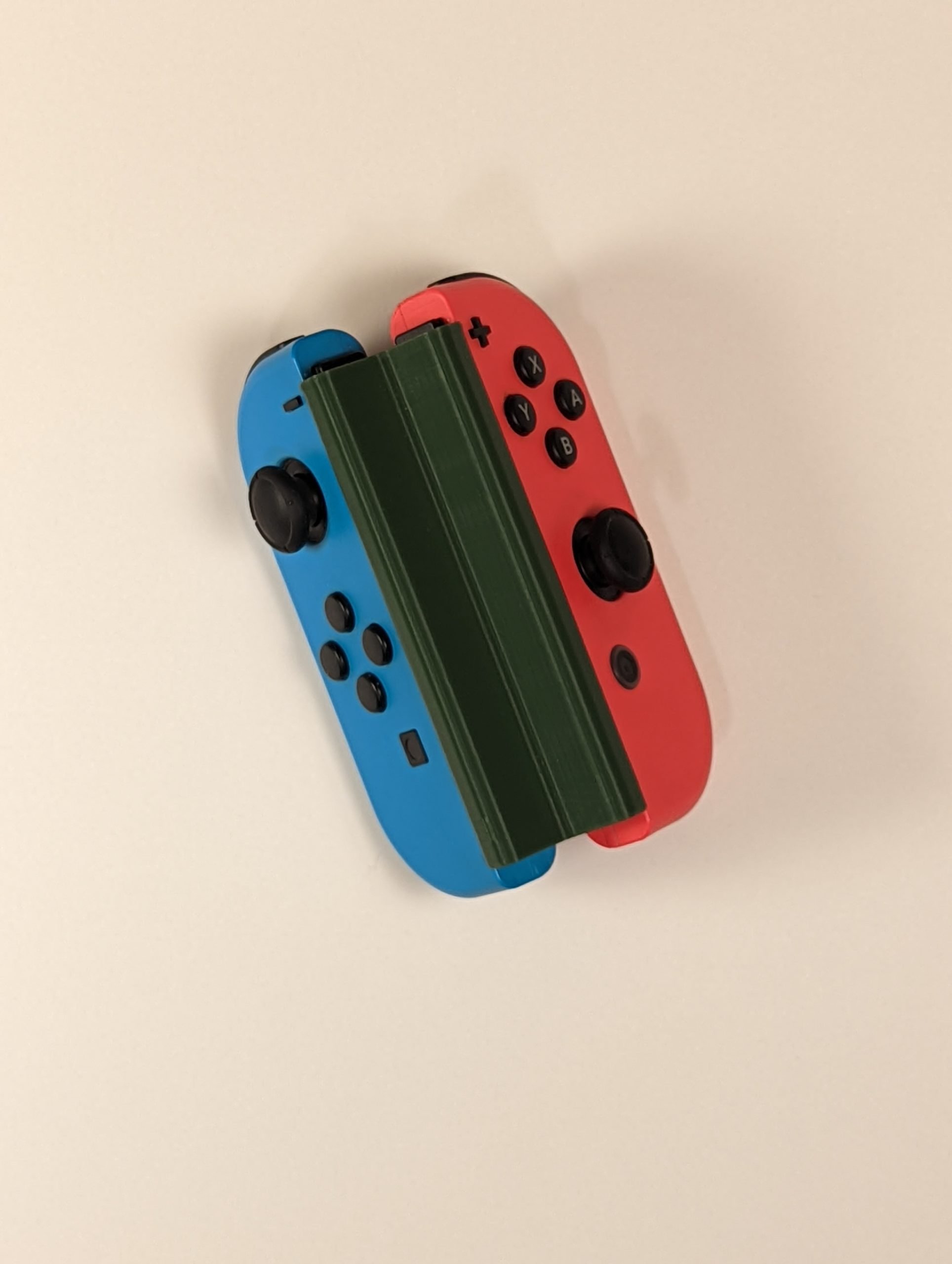 Blue and red Nintendo Switch joy-cons connected together by a green 3D printed controller adaptation