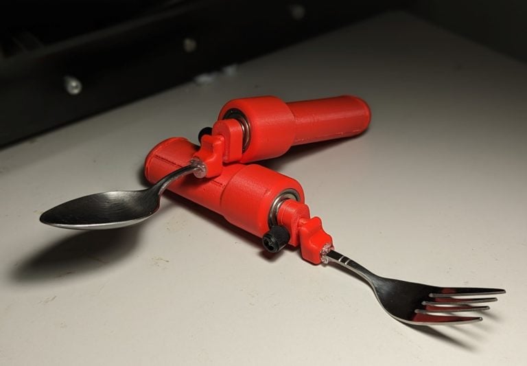 A red spoon stabilizer being used to support a spoon and fork.