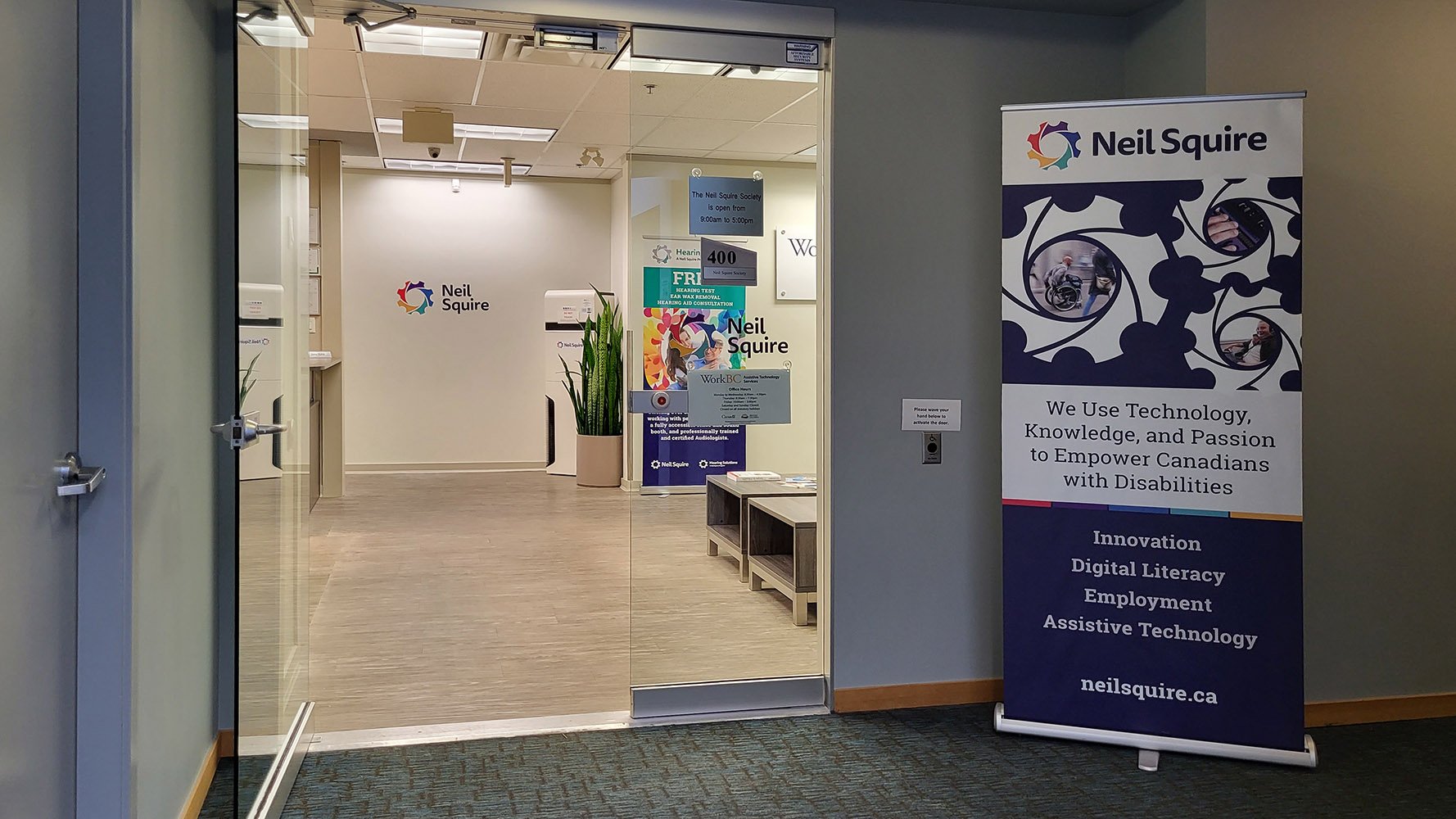 Entrance of the Neil Squire Burnaby Office with a large Neil Squire banner and glass door.