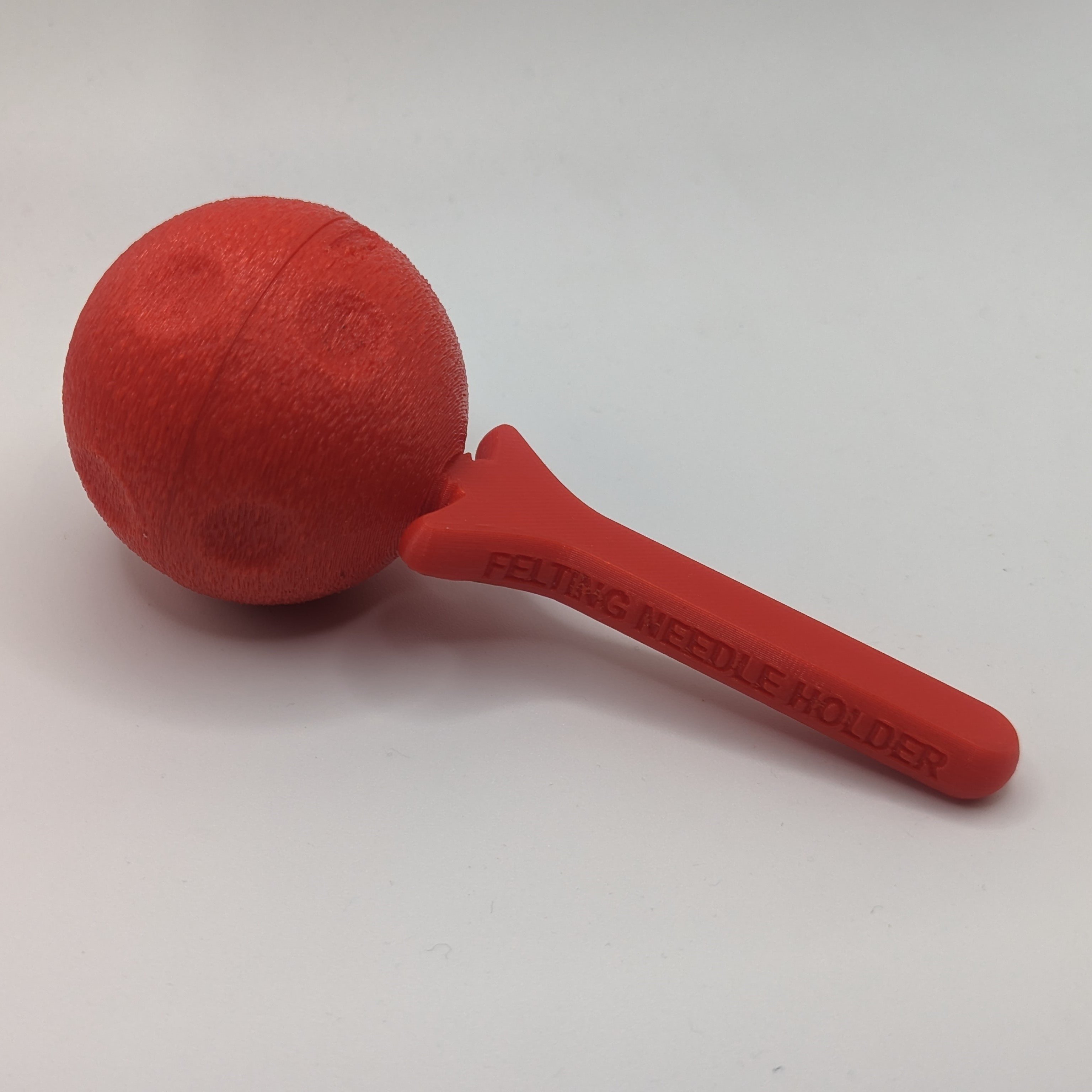 A ball shaped Felting Needle Holder in a red filament with the cover attached.