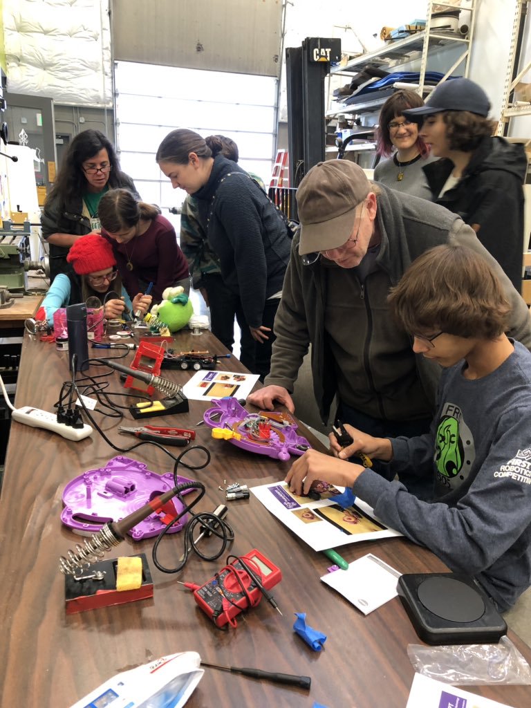 MMC staff and volunteers building assistive devices on a table.