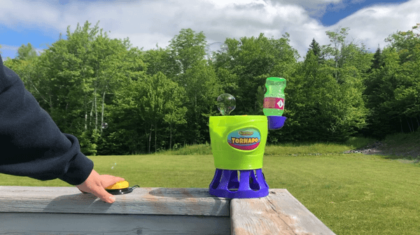 GIF of hand pressing on a yellow 3d printed assistive switch to activate a switch-adapted bubble blower.