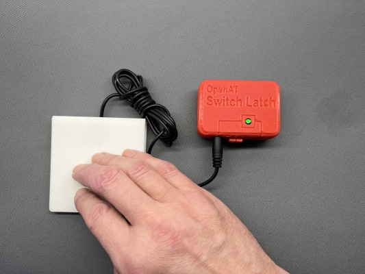 A hand using an OpenAT Switch Latch to activate another switch.