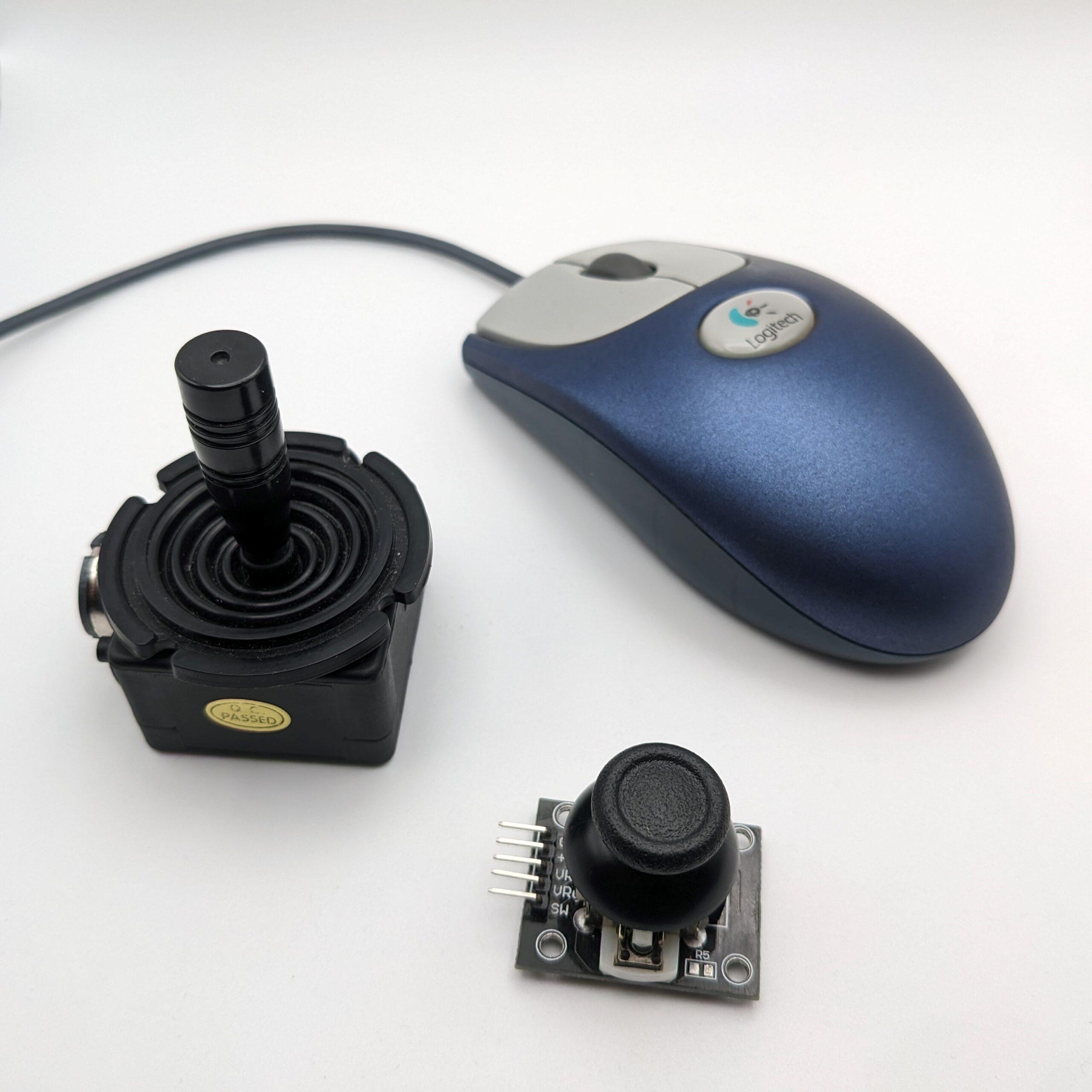 A Logitech mouse and two joysticks on a white table.