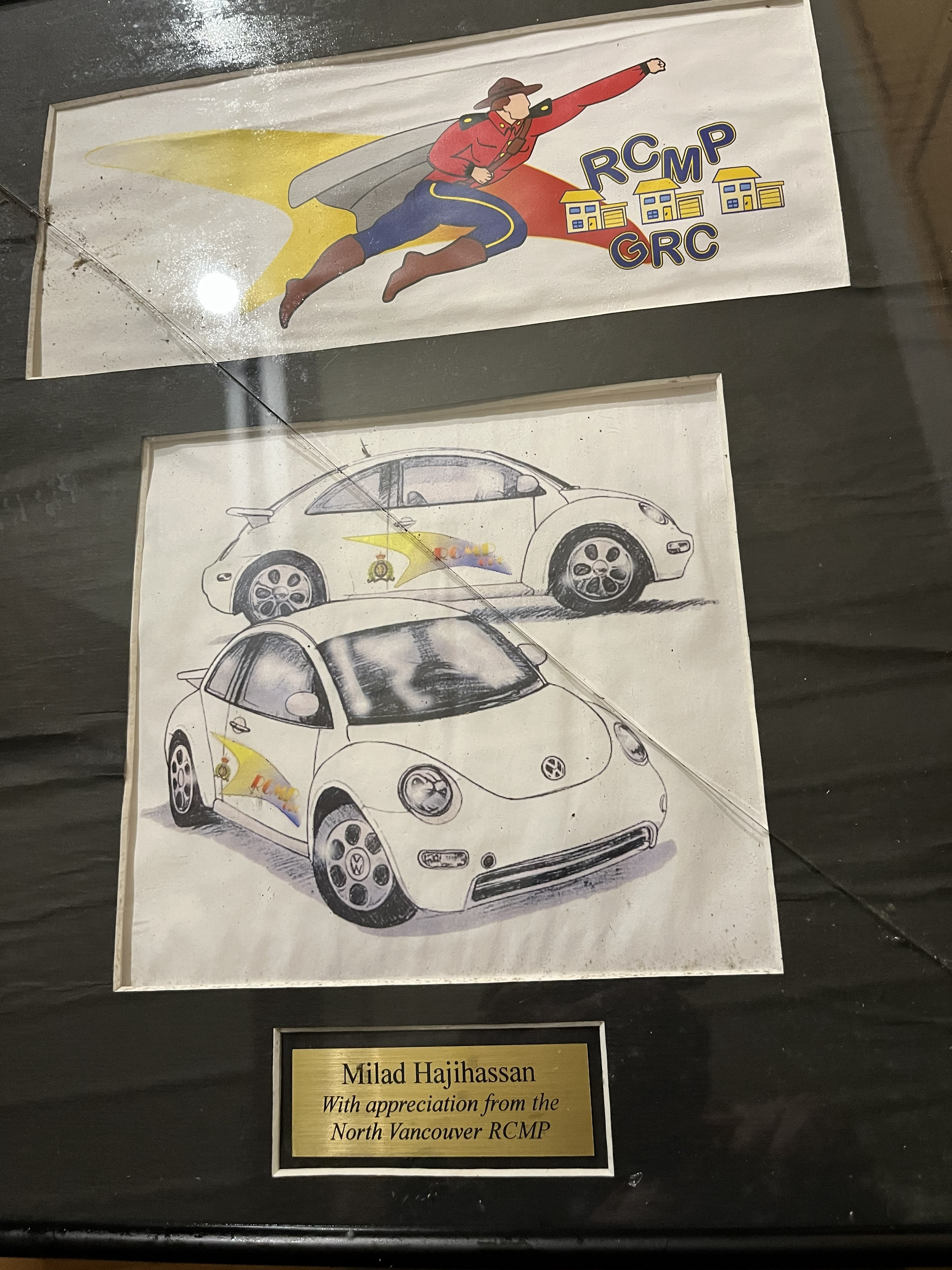 Milad's artwork — one a cartoon drawing of a Mountie flying with a cape, and the other a drawing of RCMP branded Volkswagen Beetles — framed and recognized by the North Vancouver RCMP.