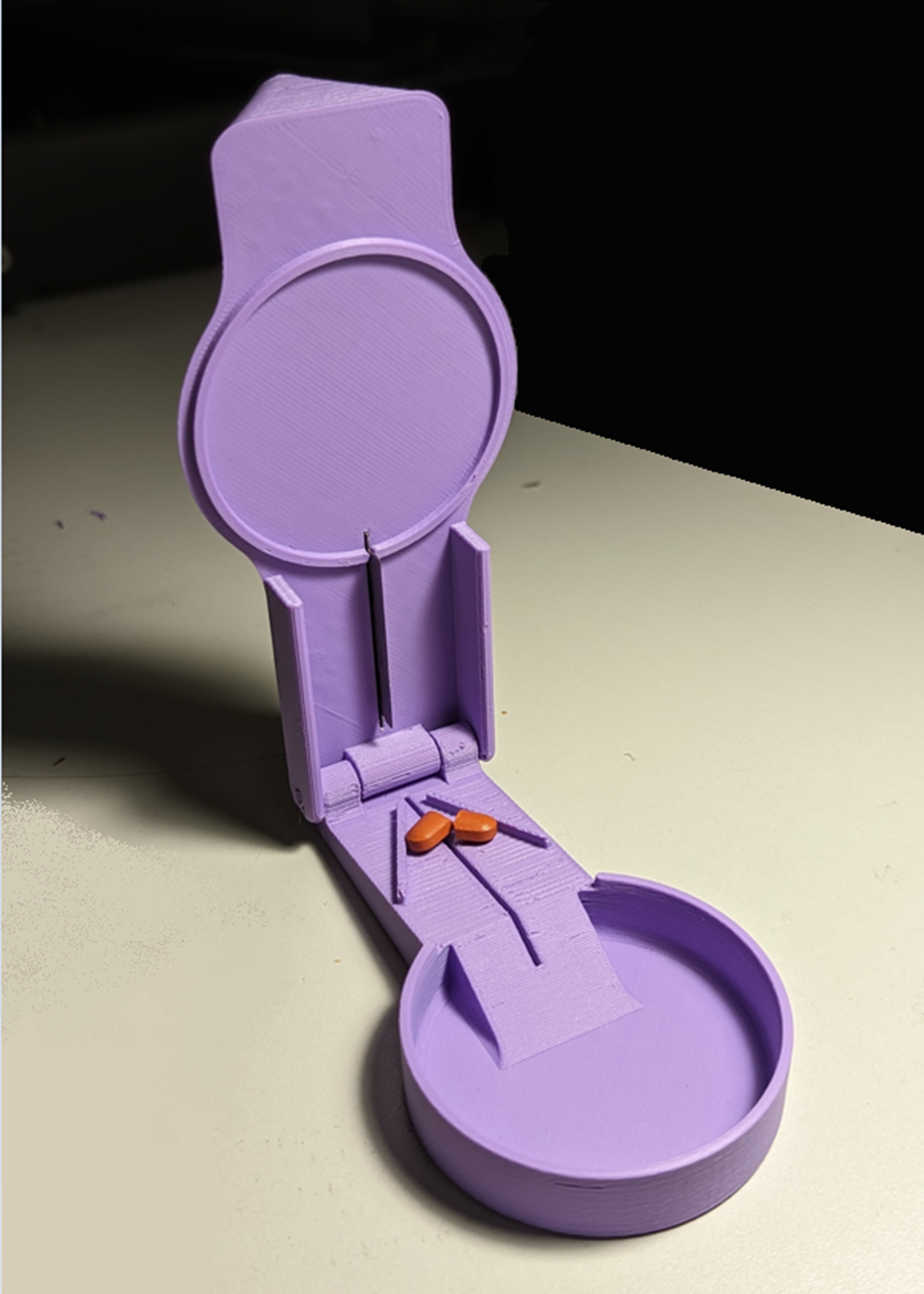 Pill splitter in the open position with a pill inside that has be cut into 2 pieces