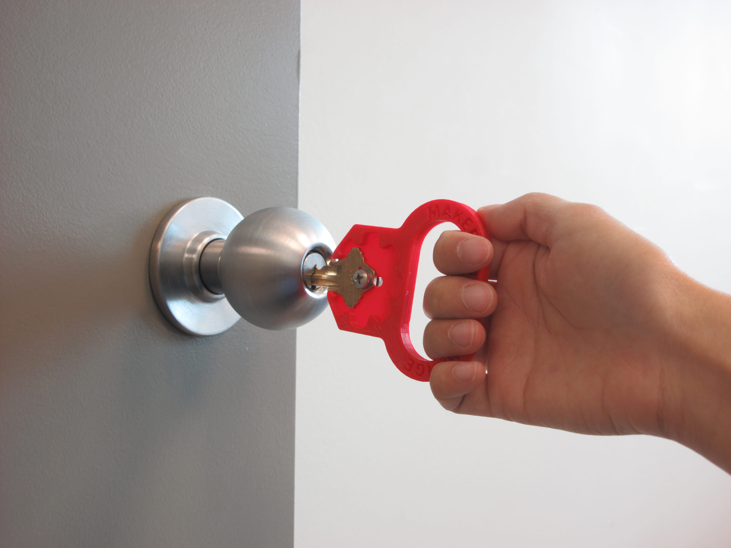 A hand using a red 3D Printed key turner