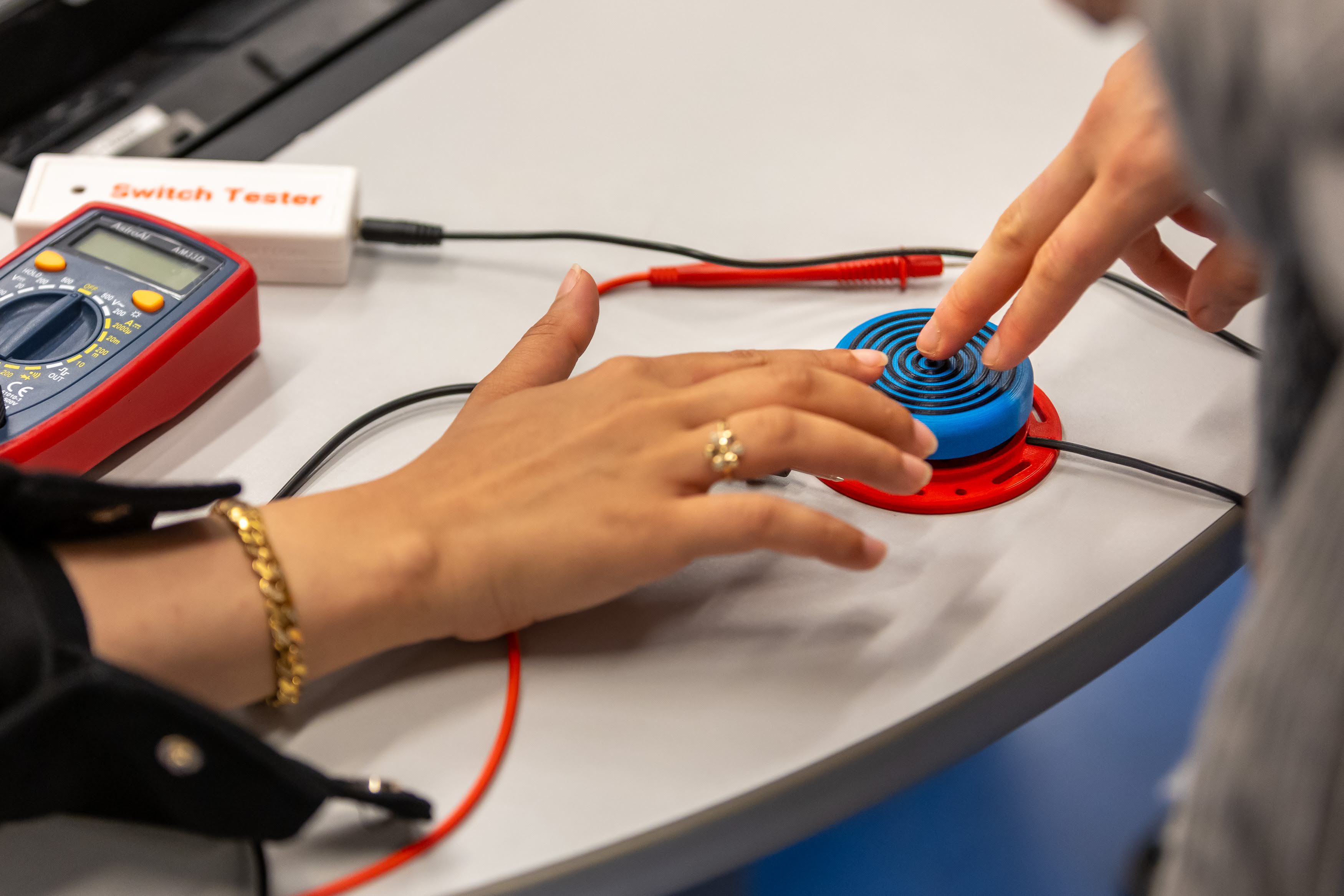 A hand pushing a blue assistive switch.
