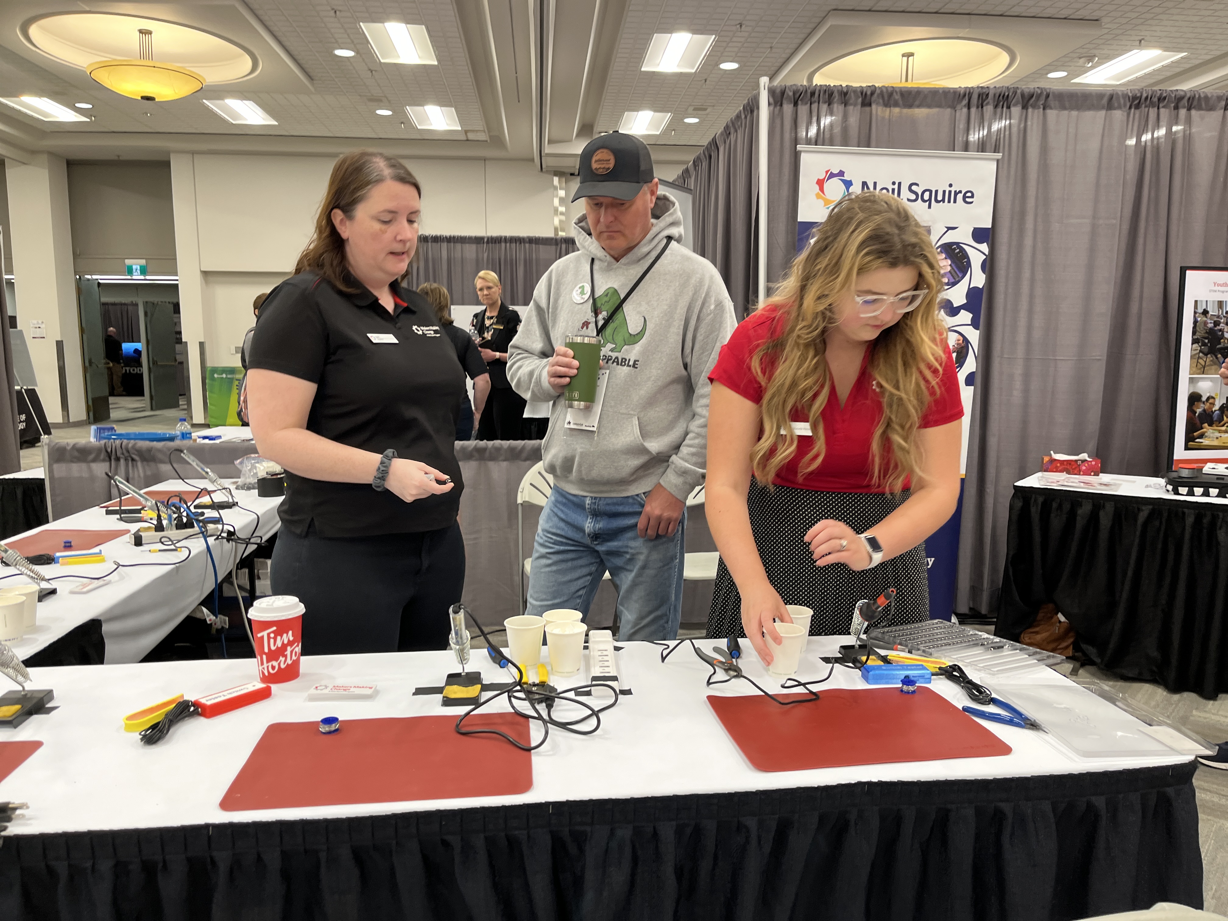 Two MMC staff and Russ, founder of Creation Nation Makerspace, at a booth table