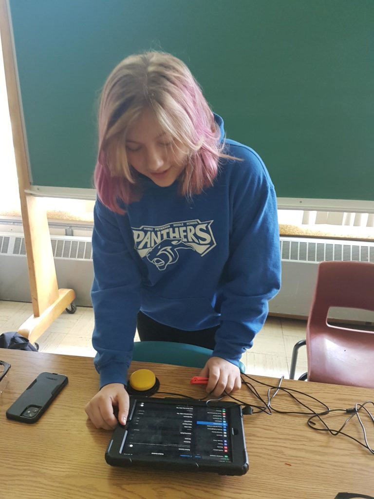 A child looking down at a table containing two assistive switches.