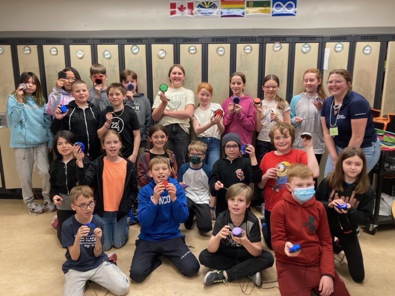 A group of children pictured in front of their lockers holding up their assistive devices.