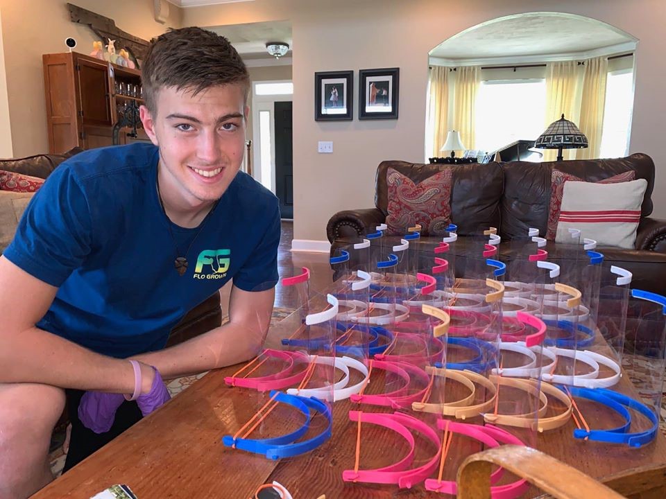 A volunteer posing beside a table of safety caps.