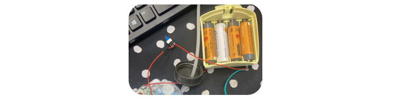 A toy opened to showcase the internal components of red wires and a blue button.