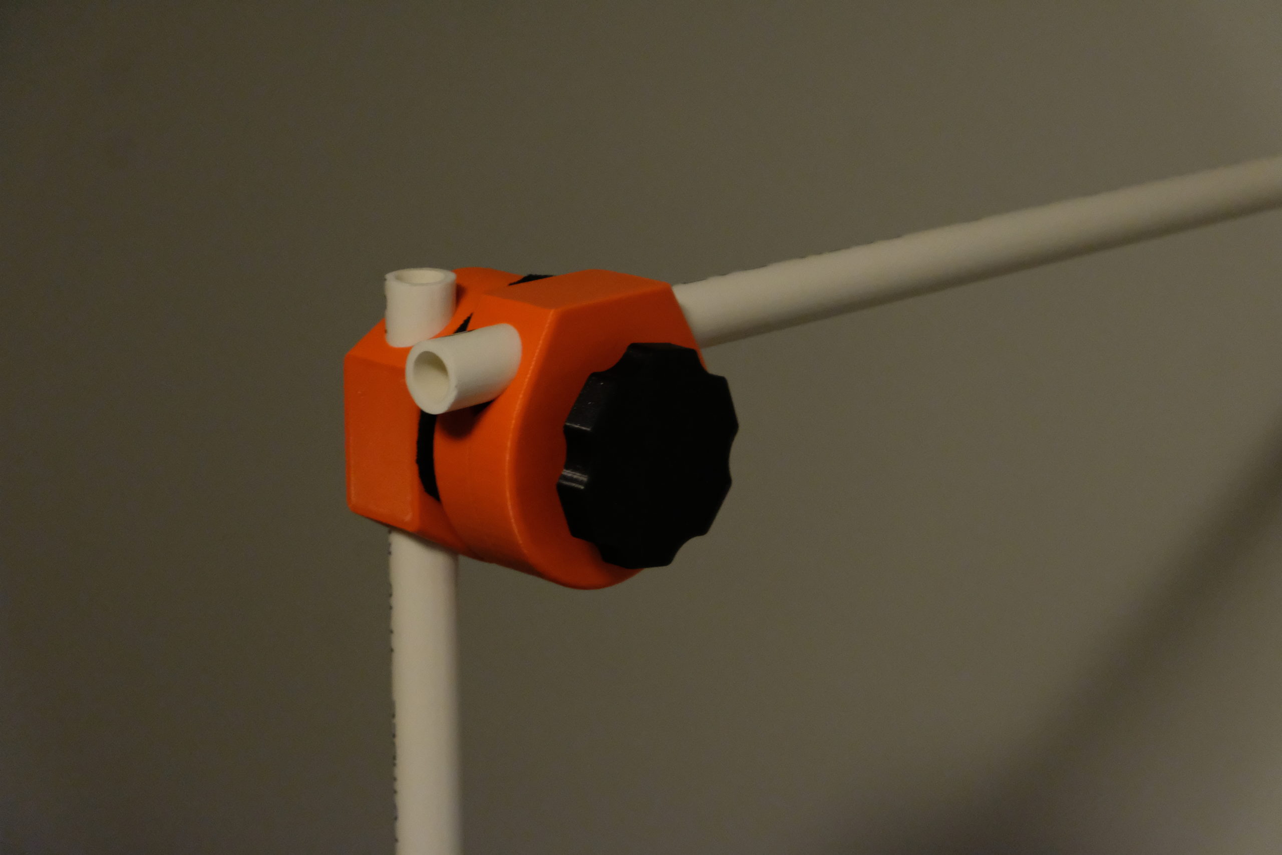 A red 3D printed lockable joint with PVC pipping against a grey background.