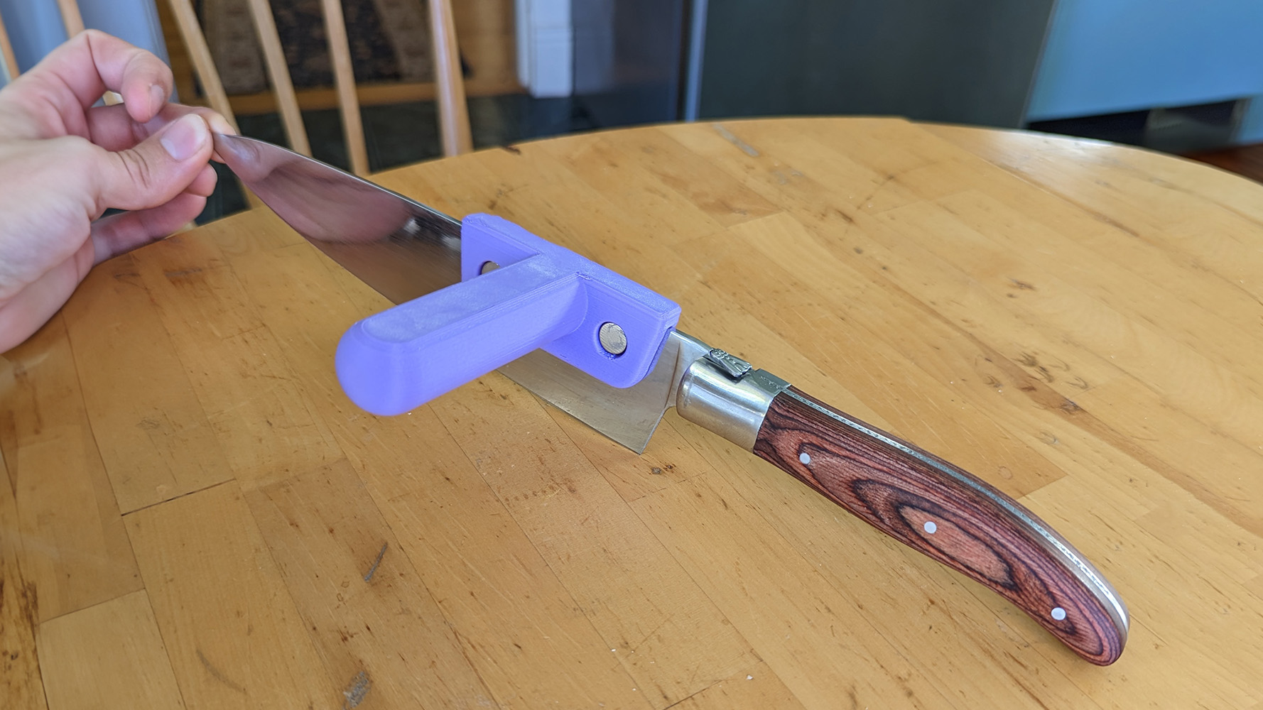 Hand holding a large kitchen knife with the knife aid installed