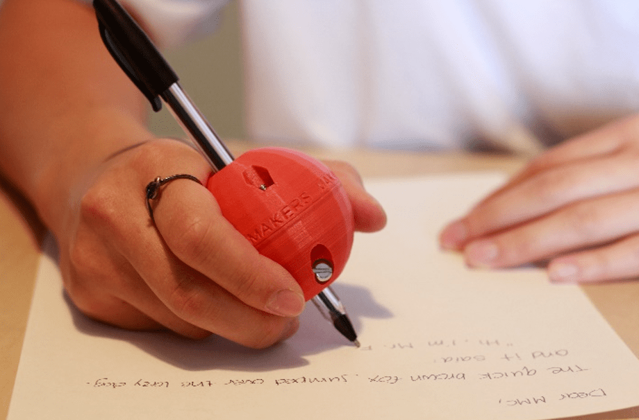 A pair of hands using a orange 3d printed pen ball to write a letter