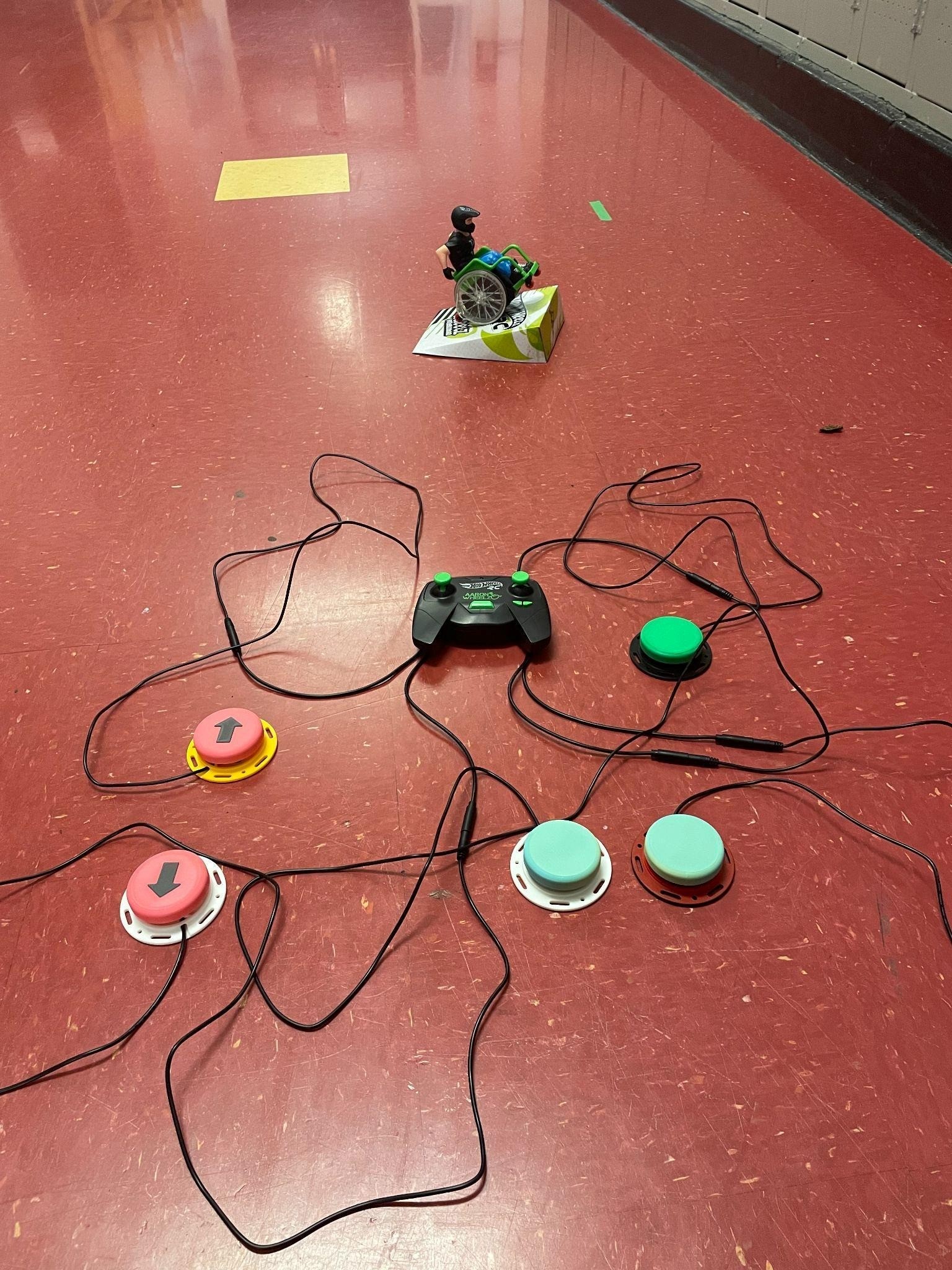 A toy of a man in a wheelchair is controlled by a controller that has been switch adapted.