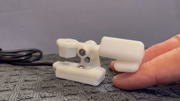 Animation of a finger resting on a table and moving upwards to slightly lift a white 3d printed lift switch.