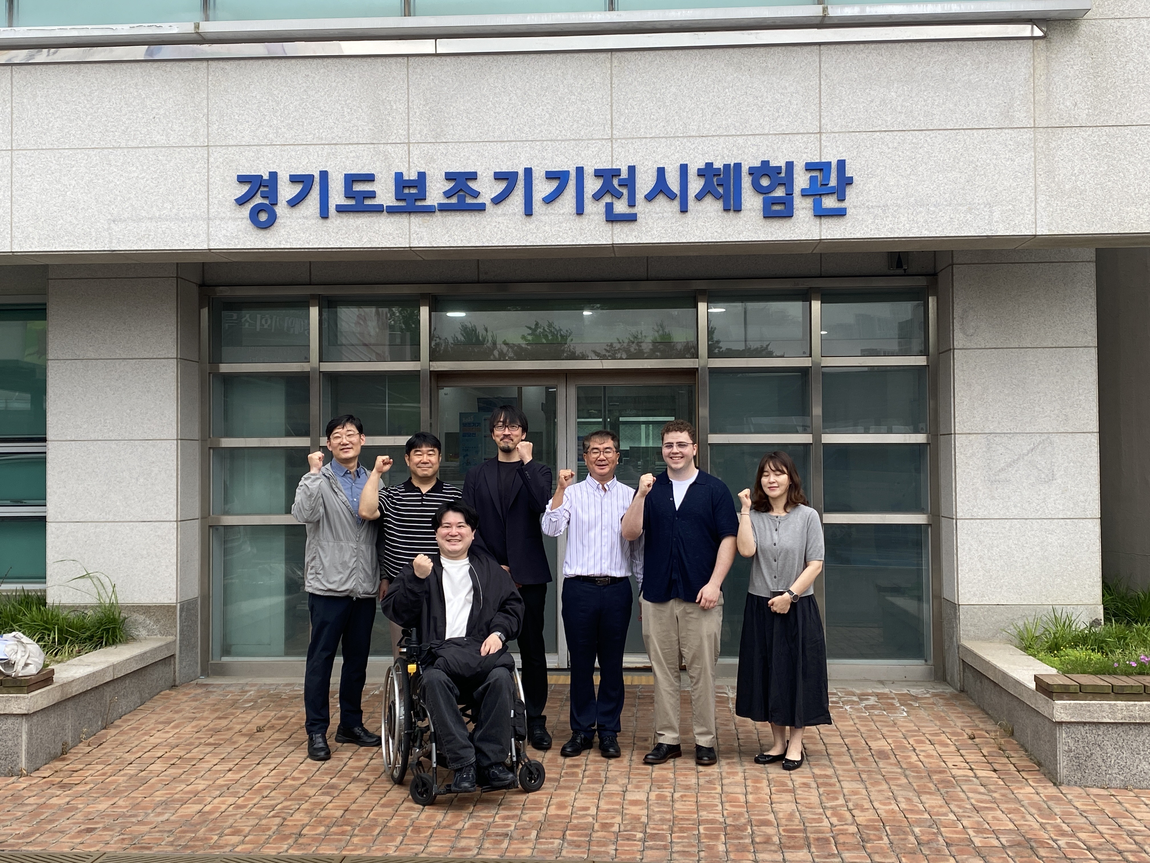 Tyler with representatives from the Gyeonggi Rehabilitation Engineering Service Research Support Center in front of the centre.