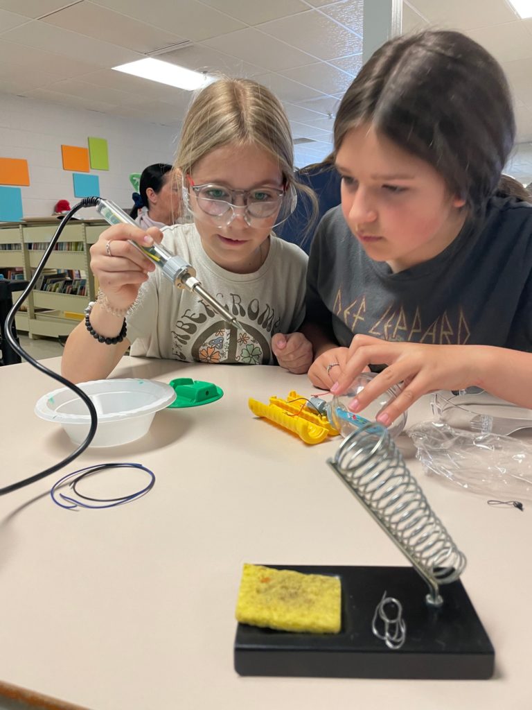 Two volunteers soldering.
