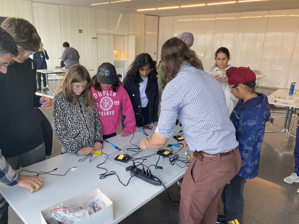Participants looking at a table with soldering irons.