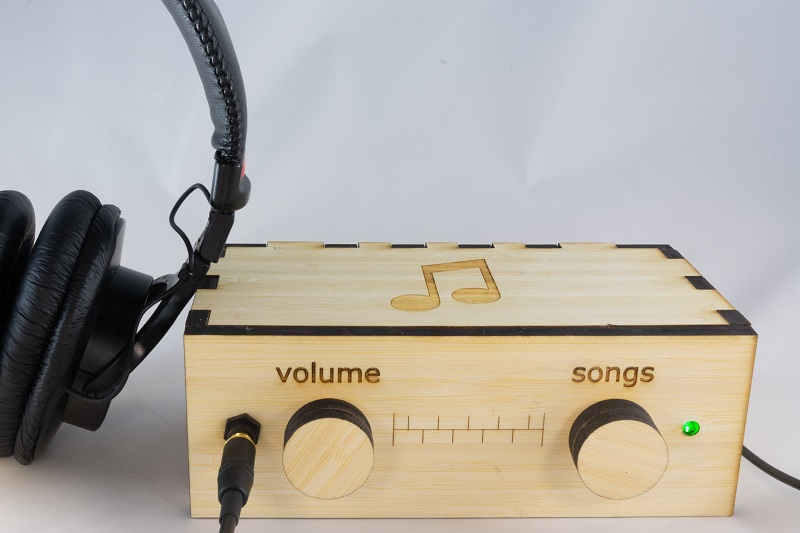 The wooden music box player with a pair of headphones.