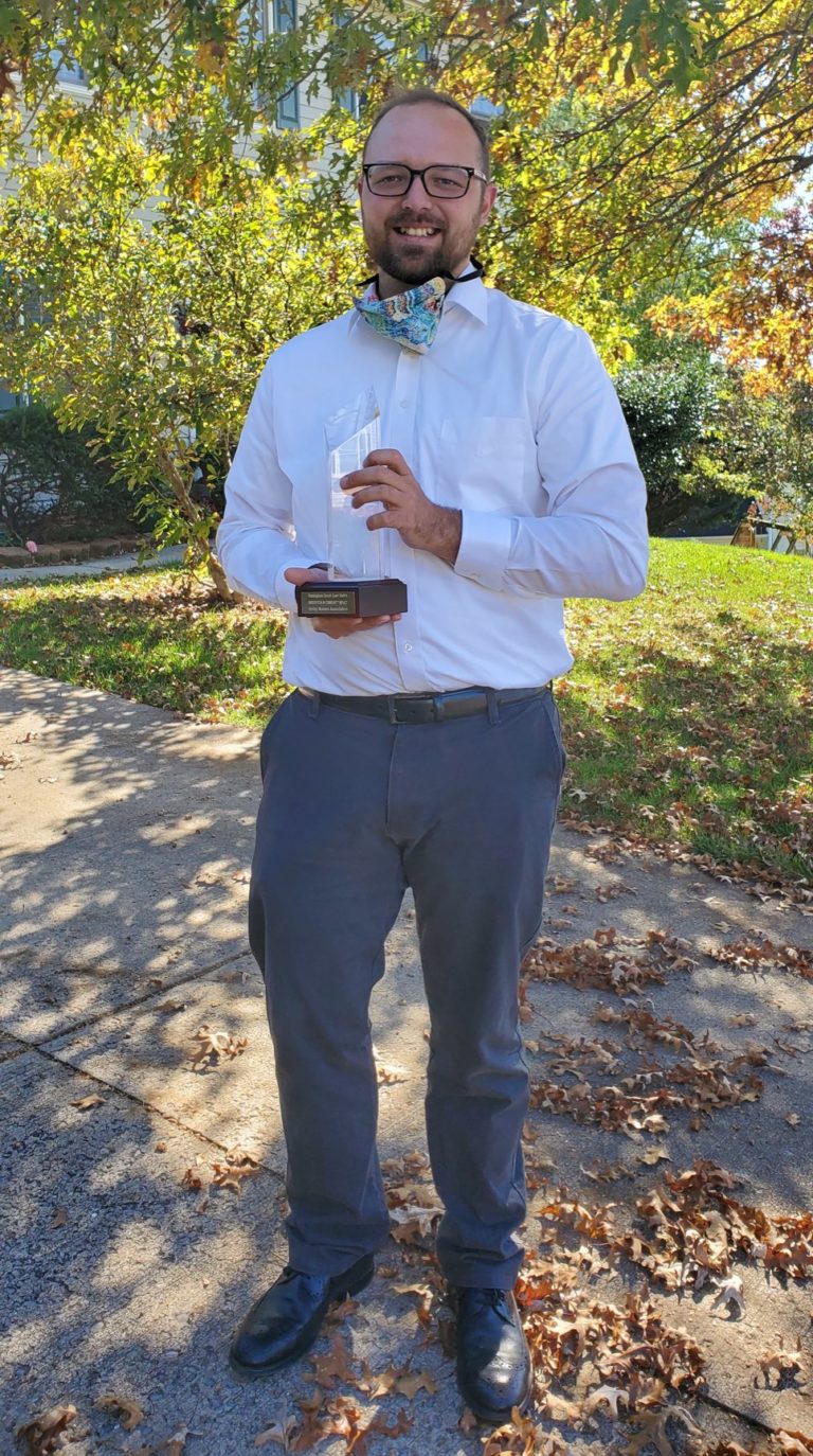 A volunteer holding an award.