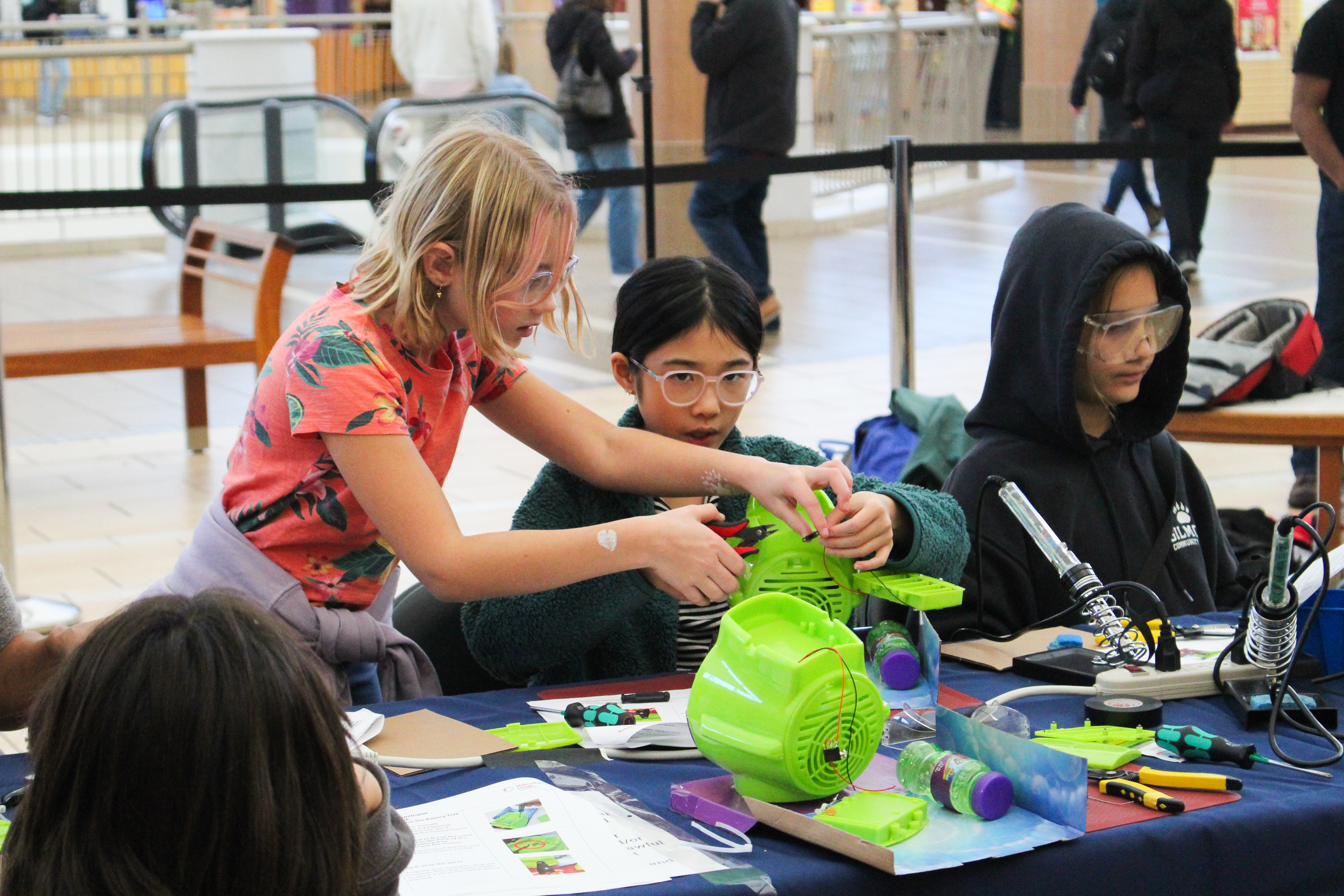 Three young girls work on a toy.