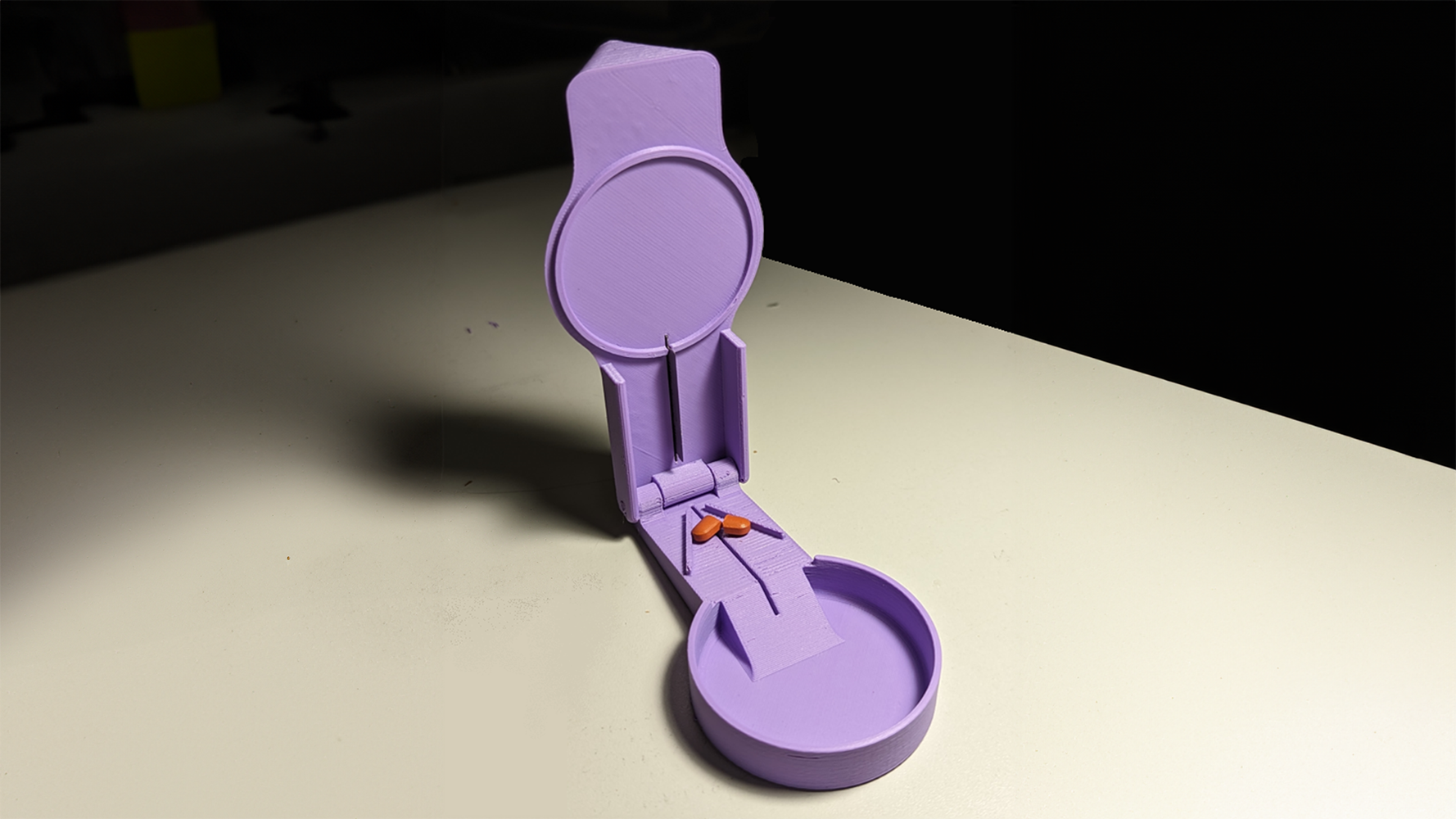 Pill splitter in the open position with a pill inside that has be cut into 2 pieces
