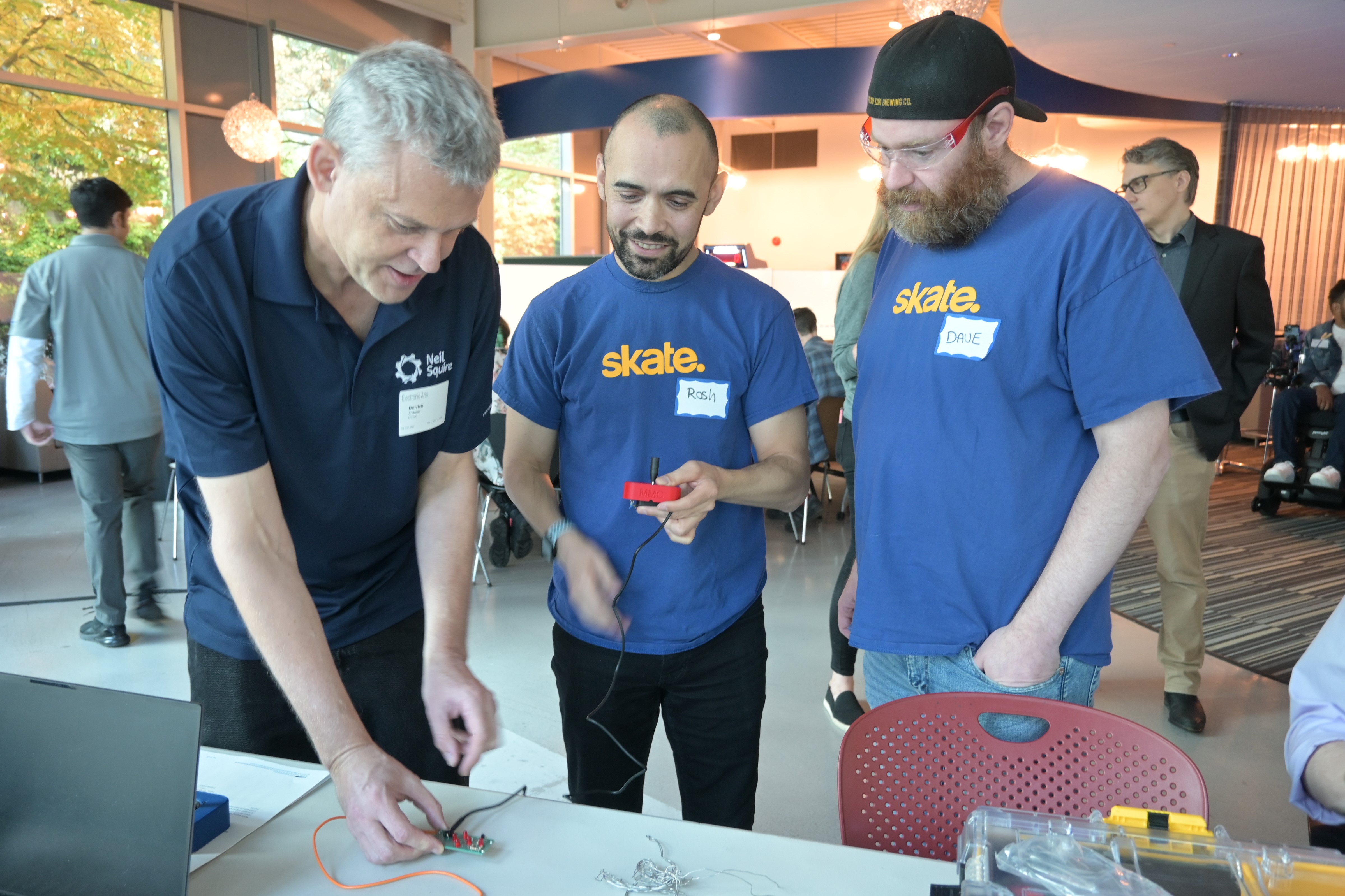 A Neil Squire staff demonstrating the joystick tester with two EA employees