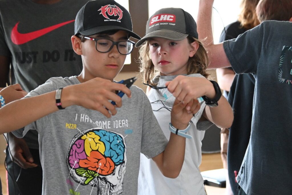 Two children using a tool to snip a wire.