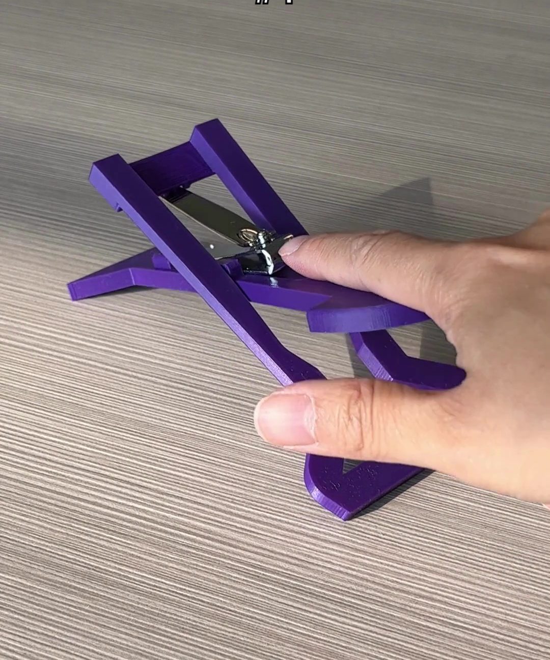 A finger on the purple 3d printed nail clipper
