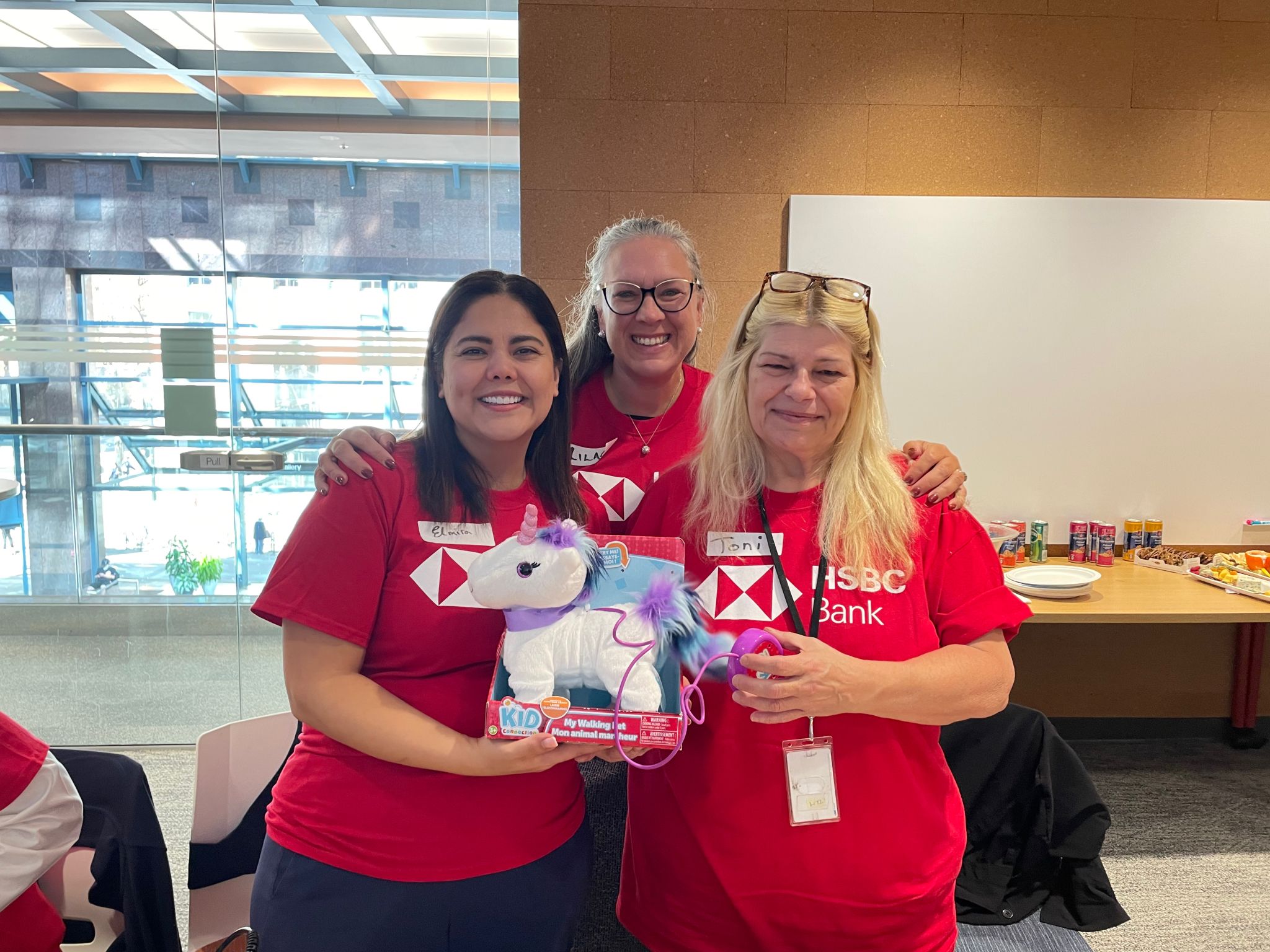 Three HSBC volunteers holding an adapted toy unicorn.