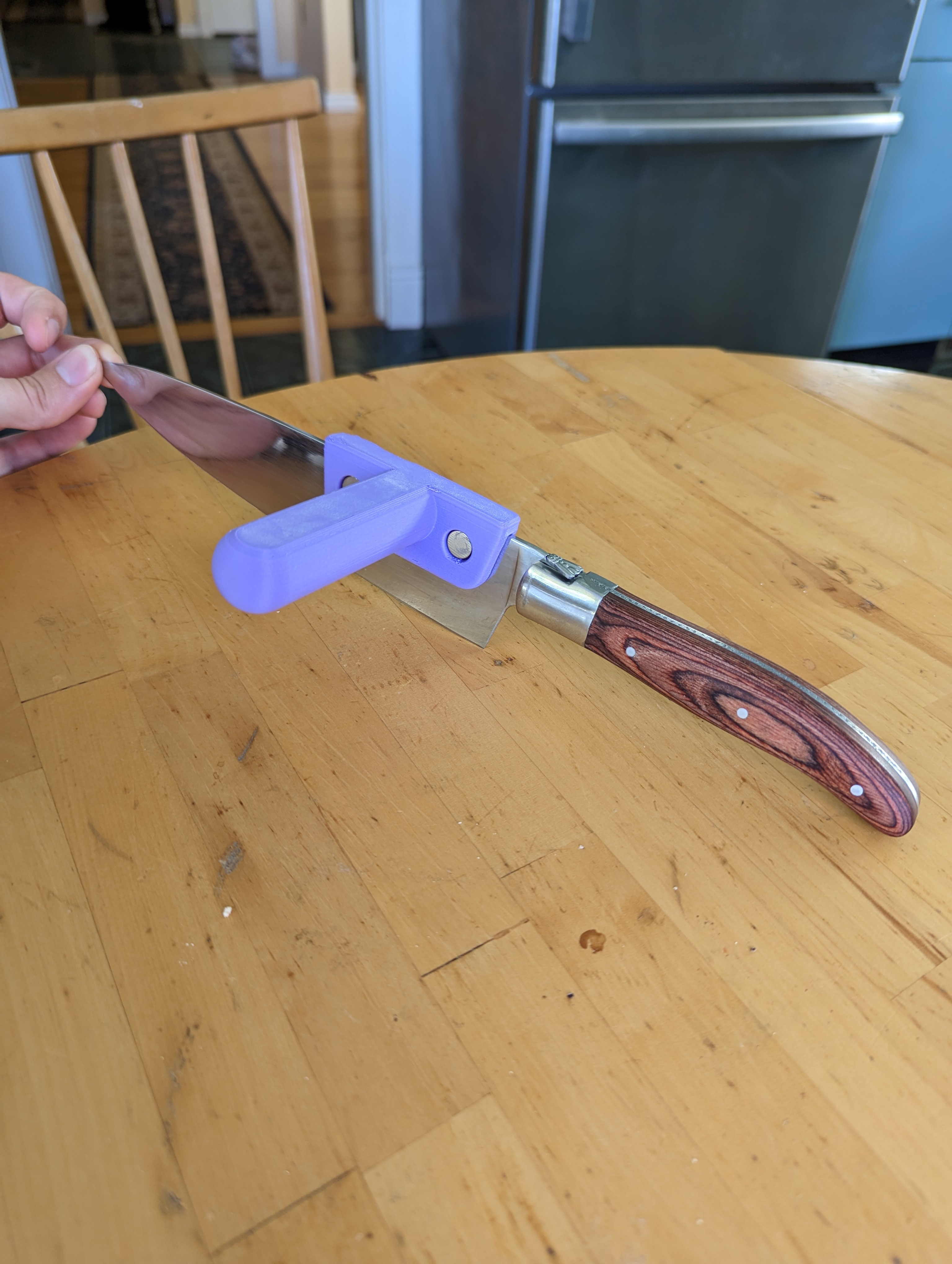Hand holding a large kitchen knife with the knife aid installed