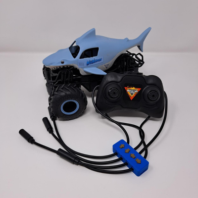 Blue shark themed remote control monster truck with a black switch adapted remote control with four mono cables coming out of it, each labeled with arrows.