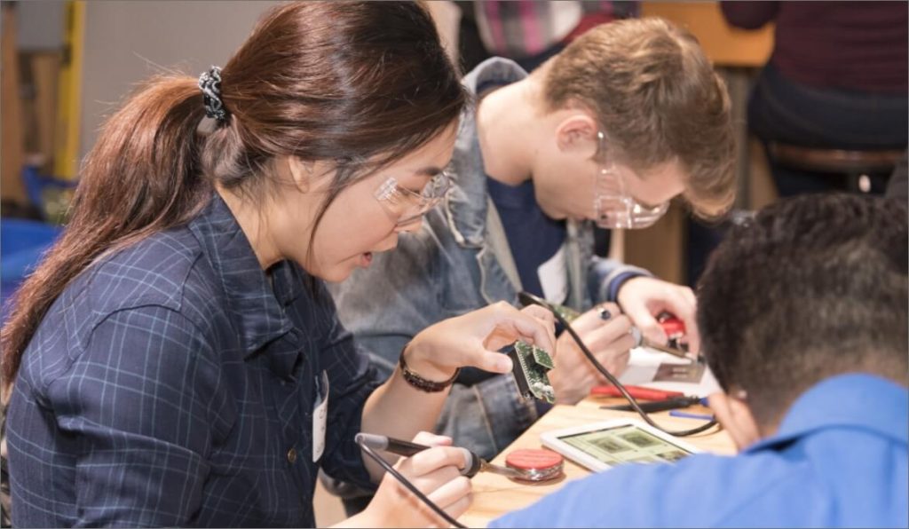 Two volunteers soldering and building assistive devices.