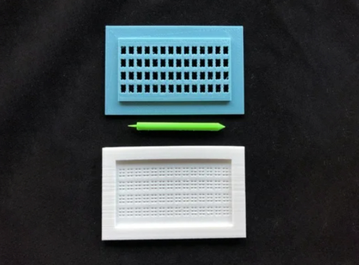 A blue and white 3d printed braille stylus set on a black cloth