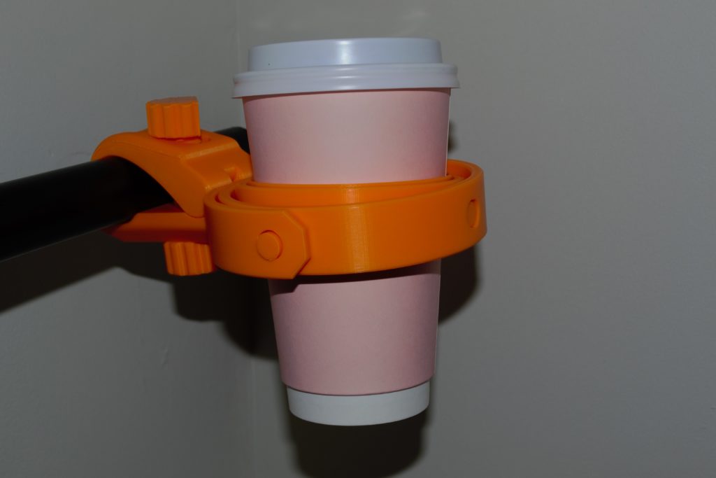 An orange cup holder holding a pink coffee cup.