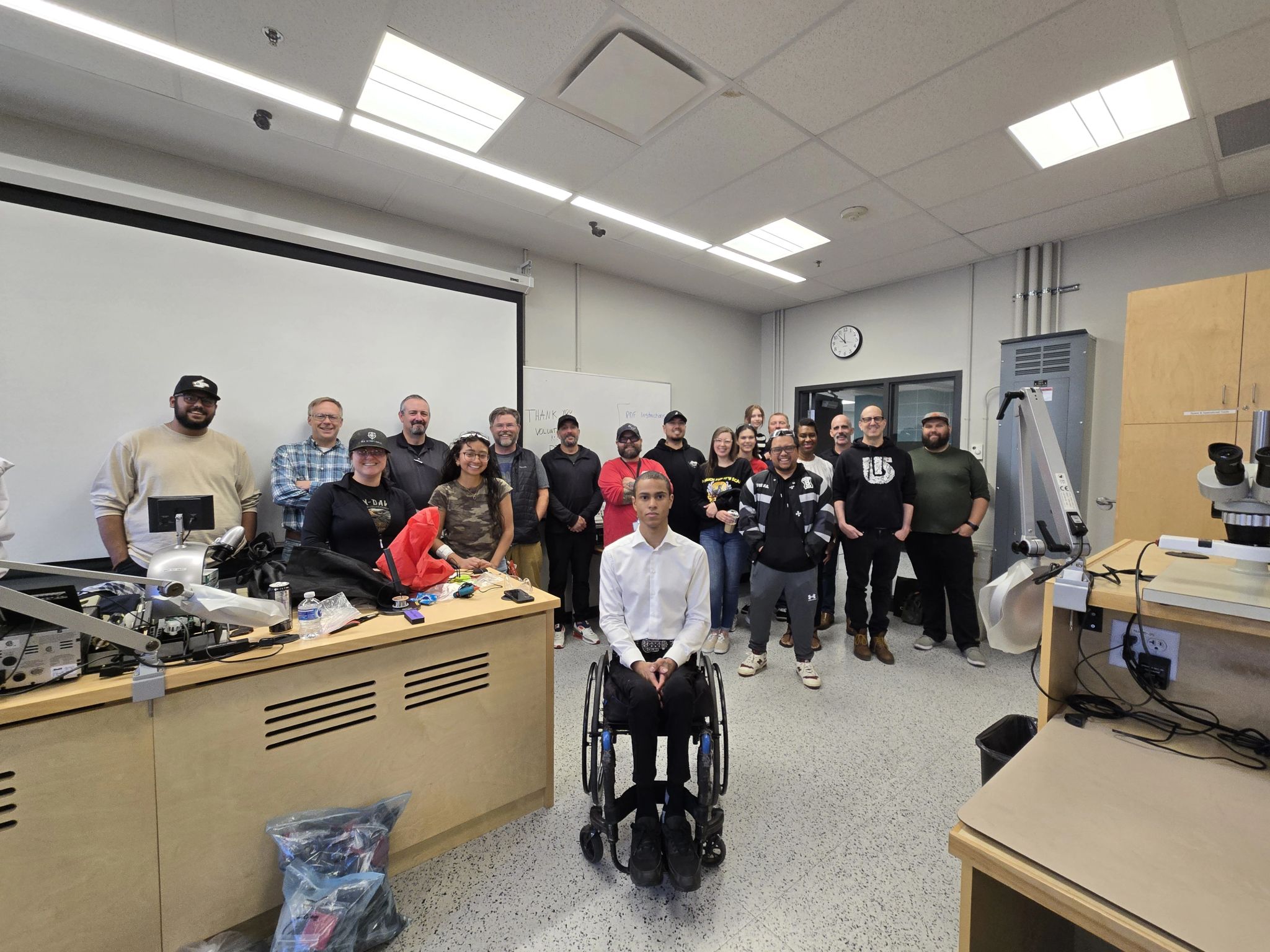 Dante in a wheelchair, in front of his group of volunteers in a classroom.
