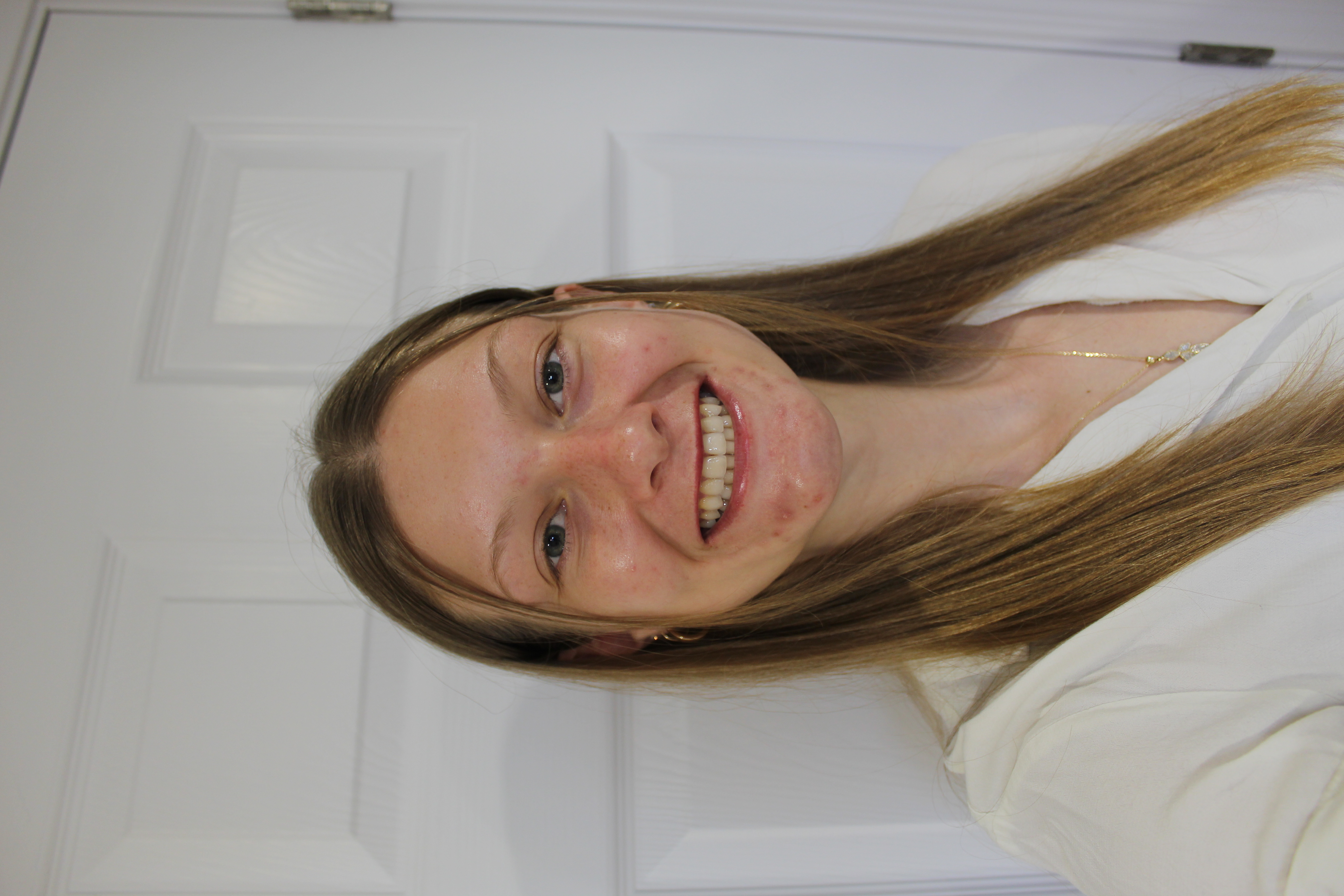 A smiling woman with brown hair and a white shirt against a white background