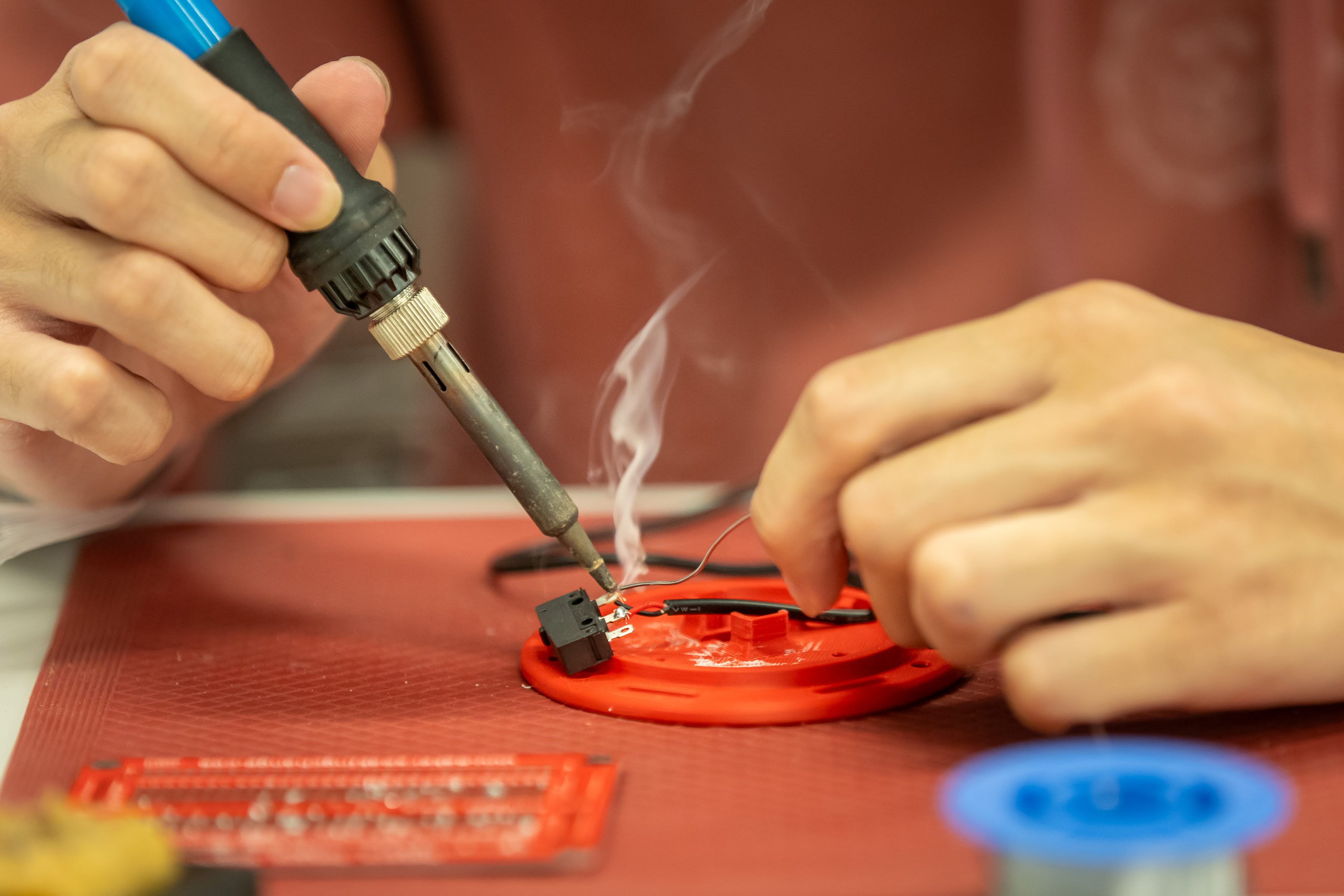 A maker using a soldering iron to work on a device.