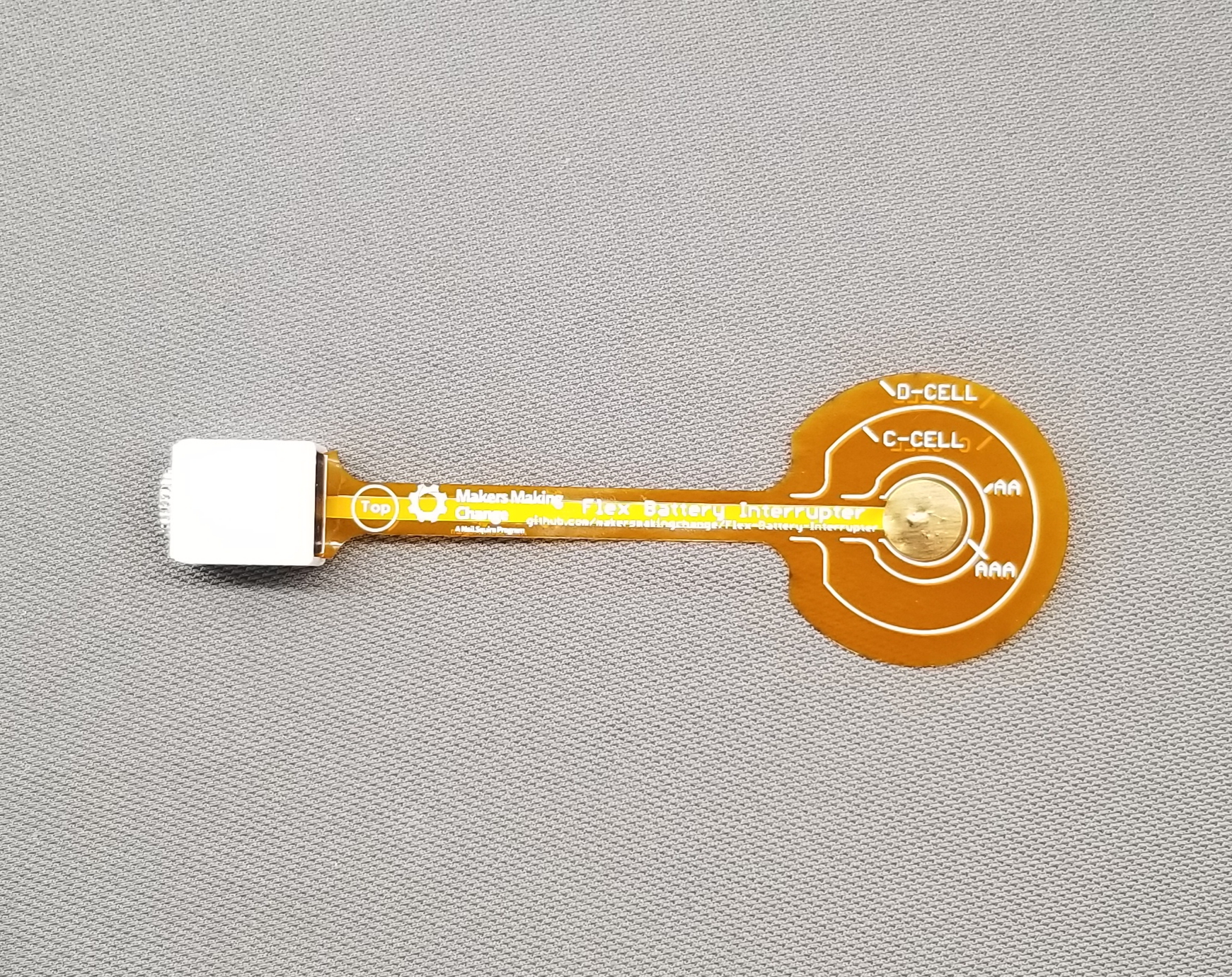 An orange flexible PCB with markings for various battery sizes and a 3d printed enclosure on end.