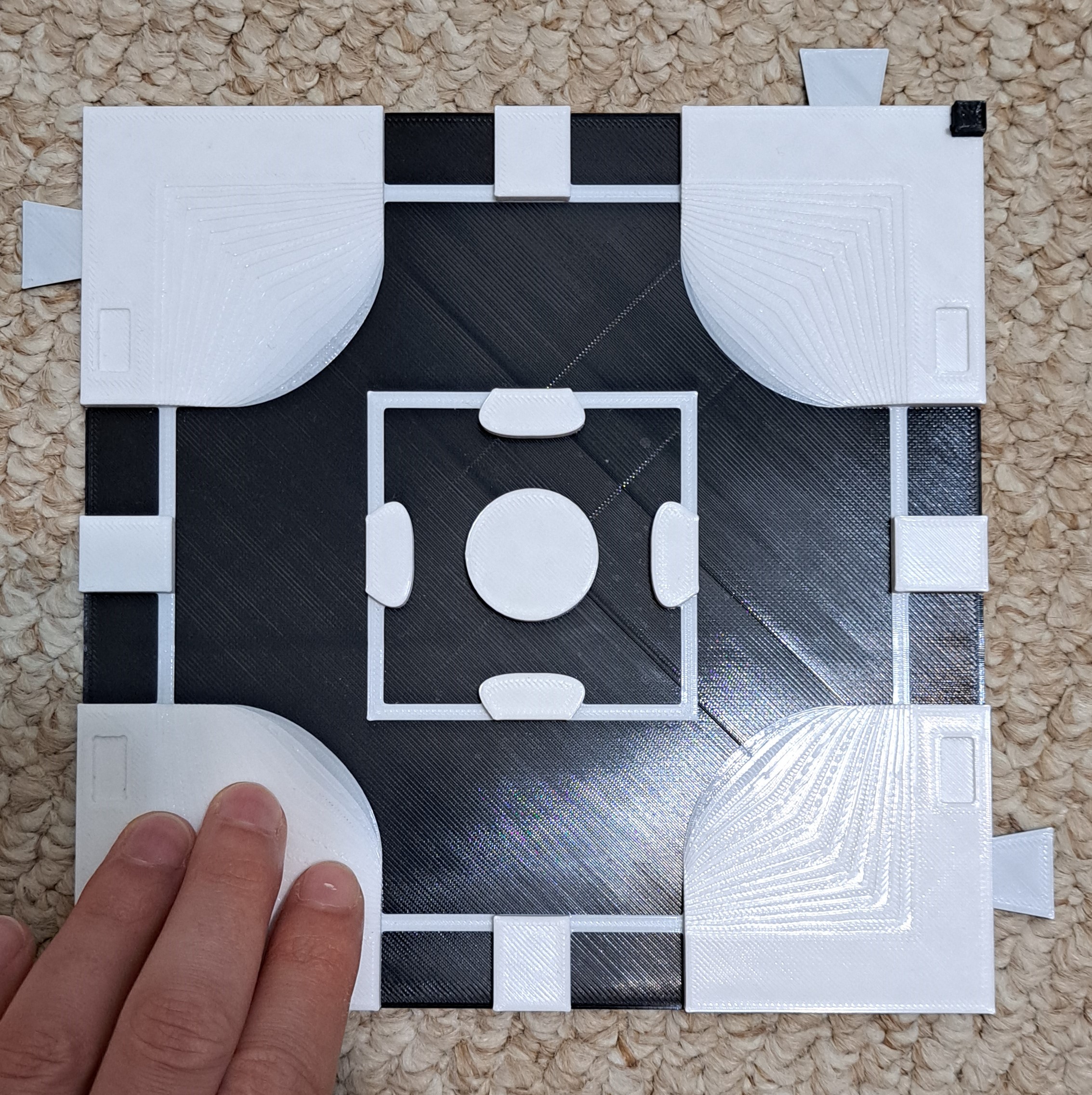 A black and white 3D Print of a road intersection with raised curbs and curb cuts