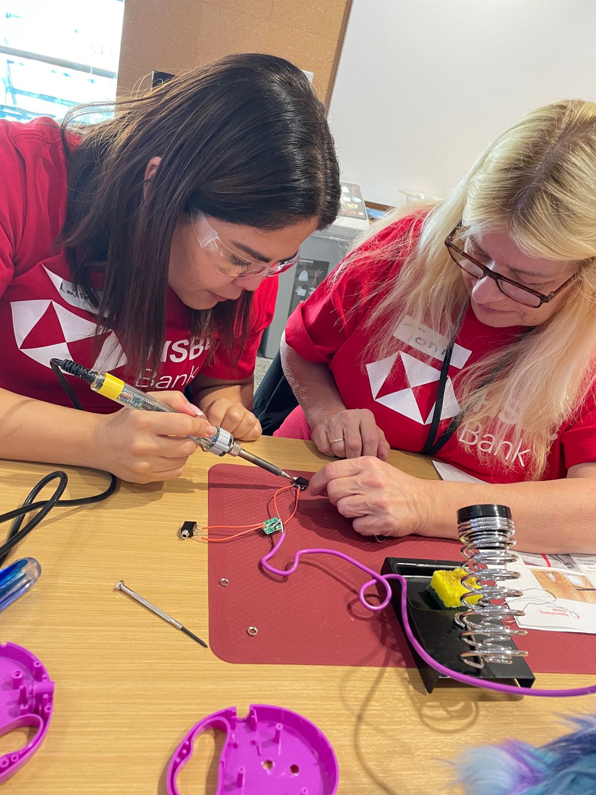 Two HSBC volunteers soldering at a table.