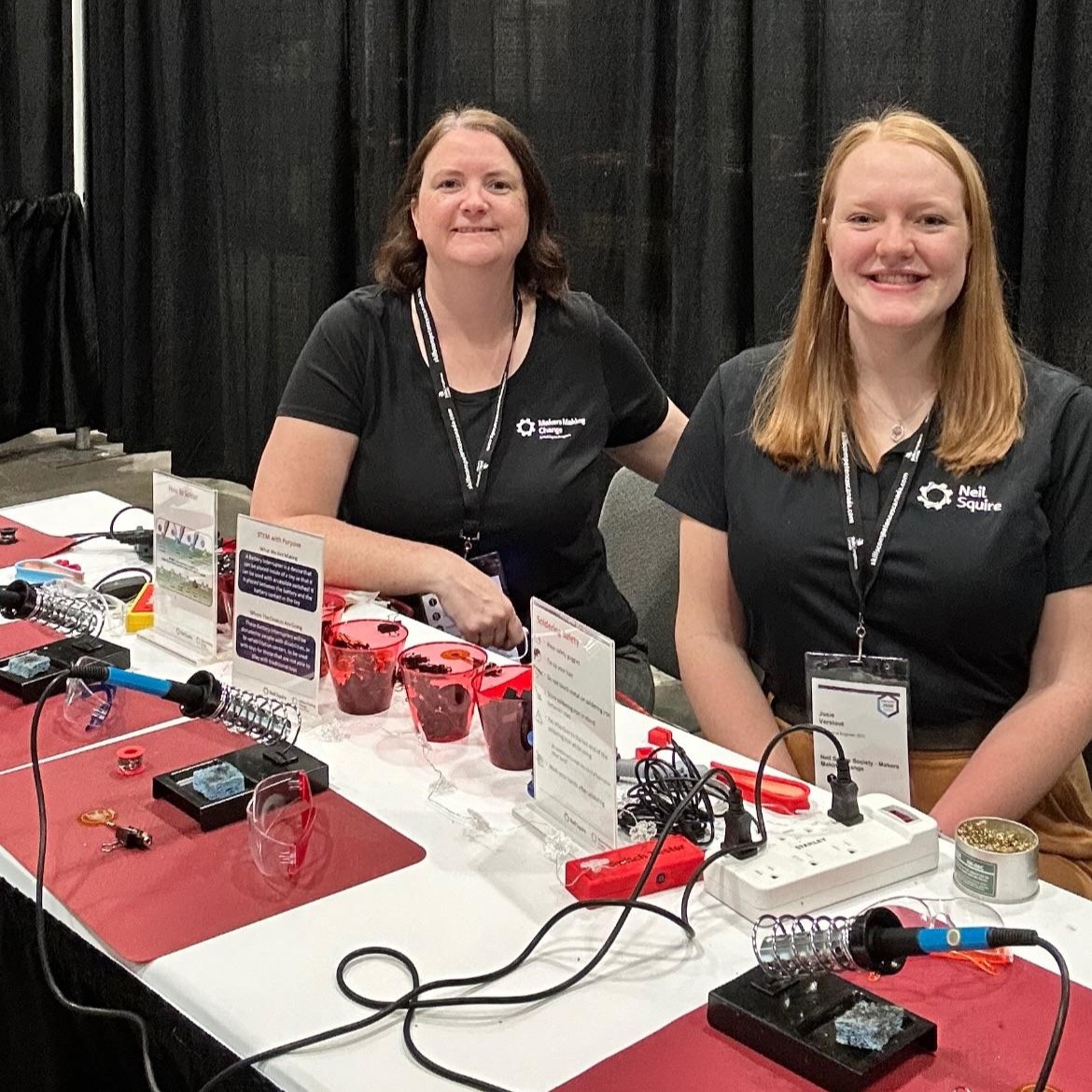 Courtney and Josie at the Makers Making Change table with soldering tools on display.