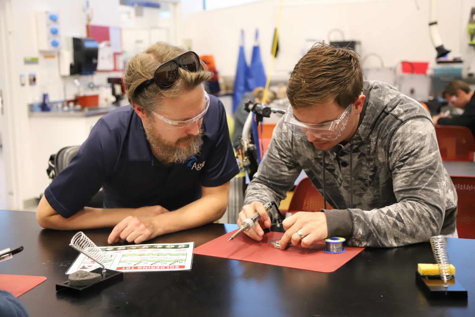 Two students examining assistive technology parts.