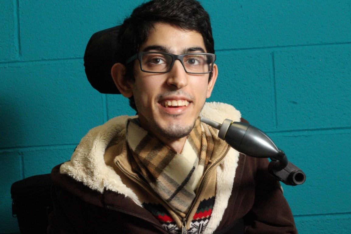Milad, in a wheelchair, pictured with the metal LipSync prototype.